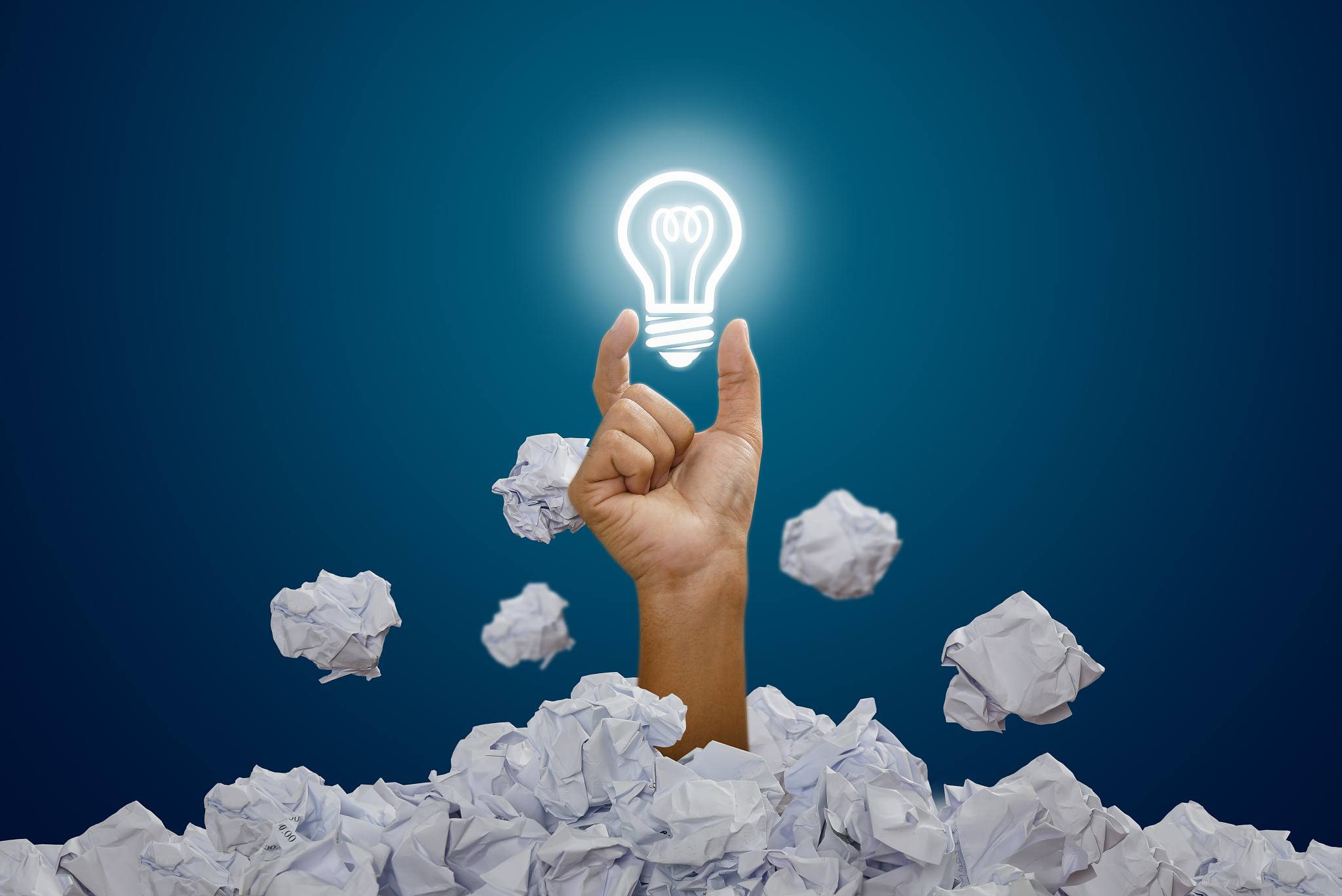 hand holding light bulb with heap of paper ball. concept of crea