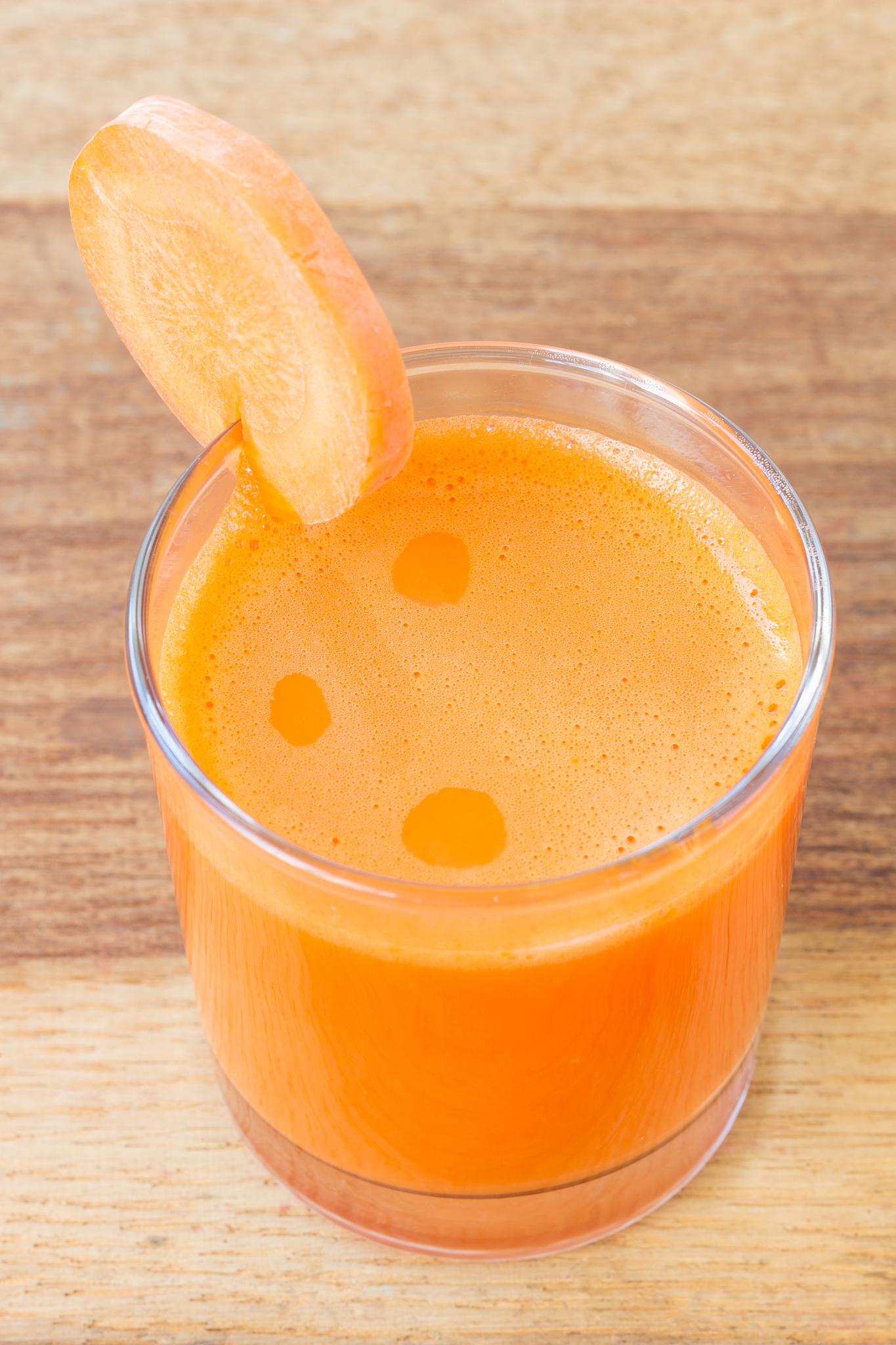 fresh carrot juice in glass on wooden table.