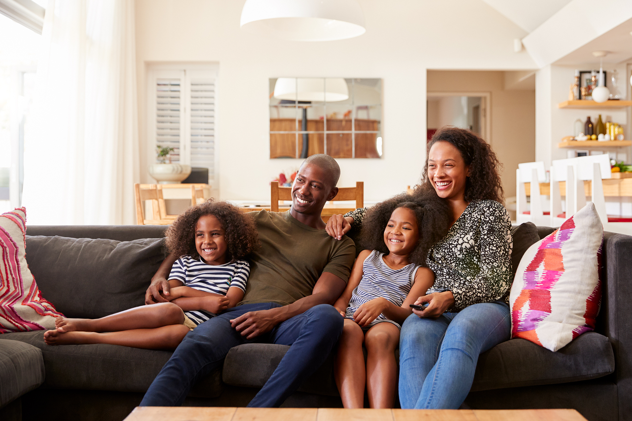 family sitting on sofa at home and watching movie on tv together