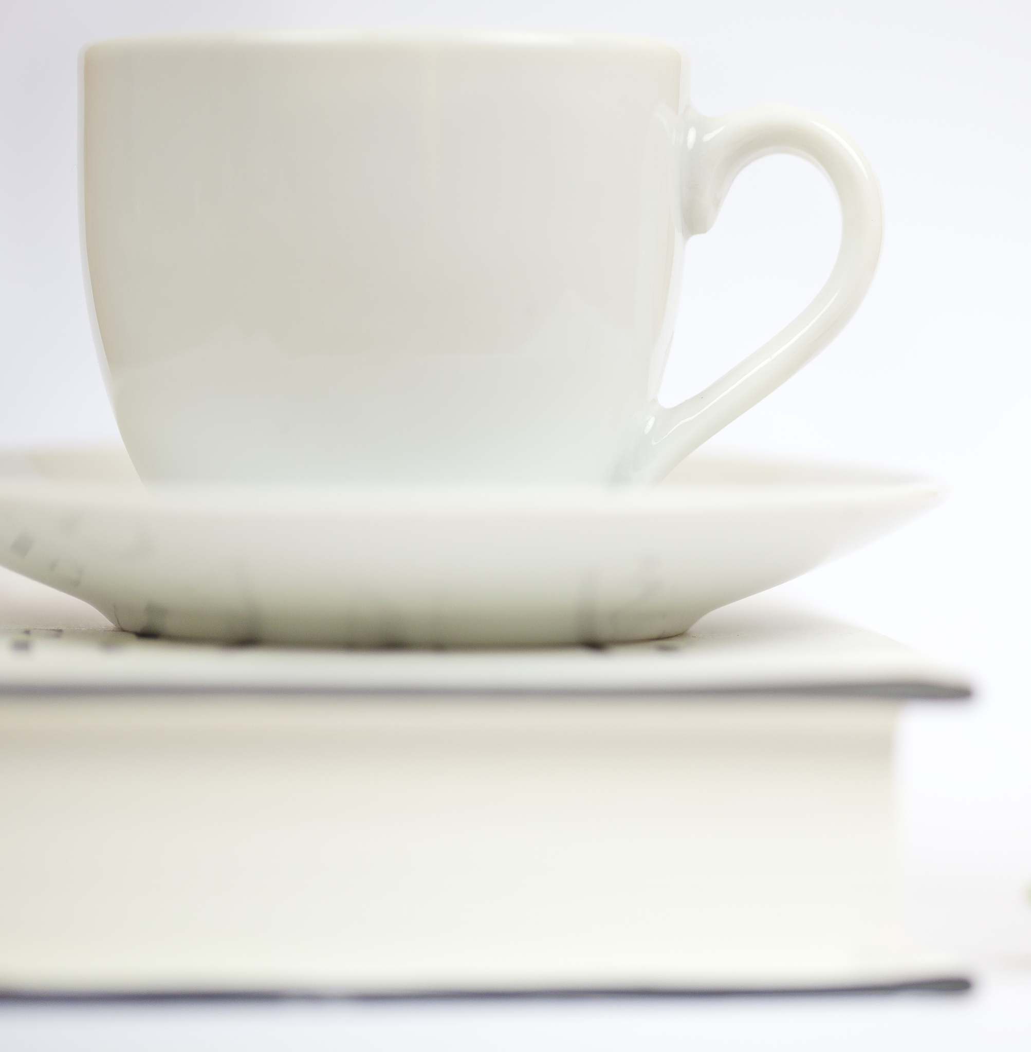 三个白色纸杯放在桌子上面 纸杯上得图案比较商务 桌子上又书本和花朵灯光比较温馨 翻译成英文