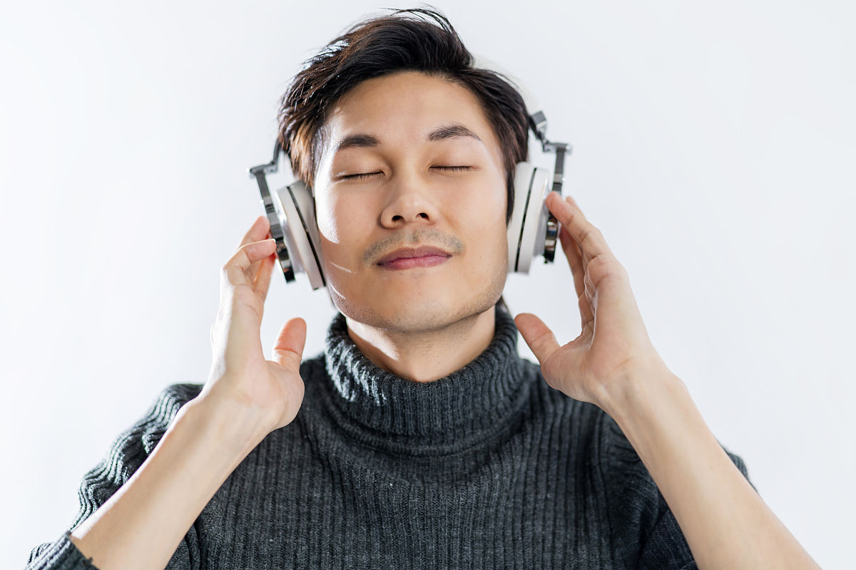 人像工作室音乐歌词概念年轻聪明的亚洲艺术家穿毛衣听耳机享受音乐音