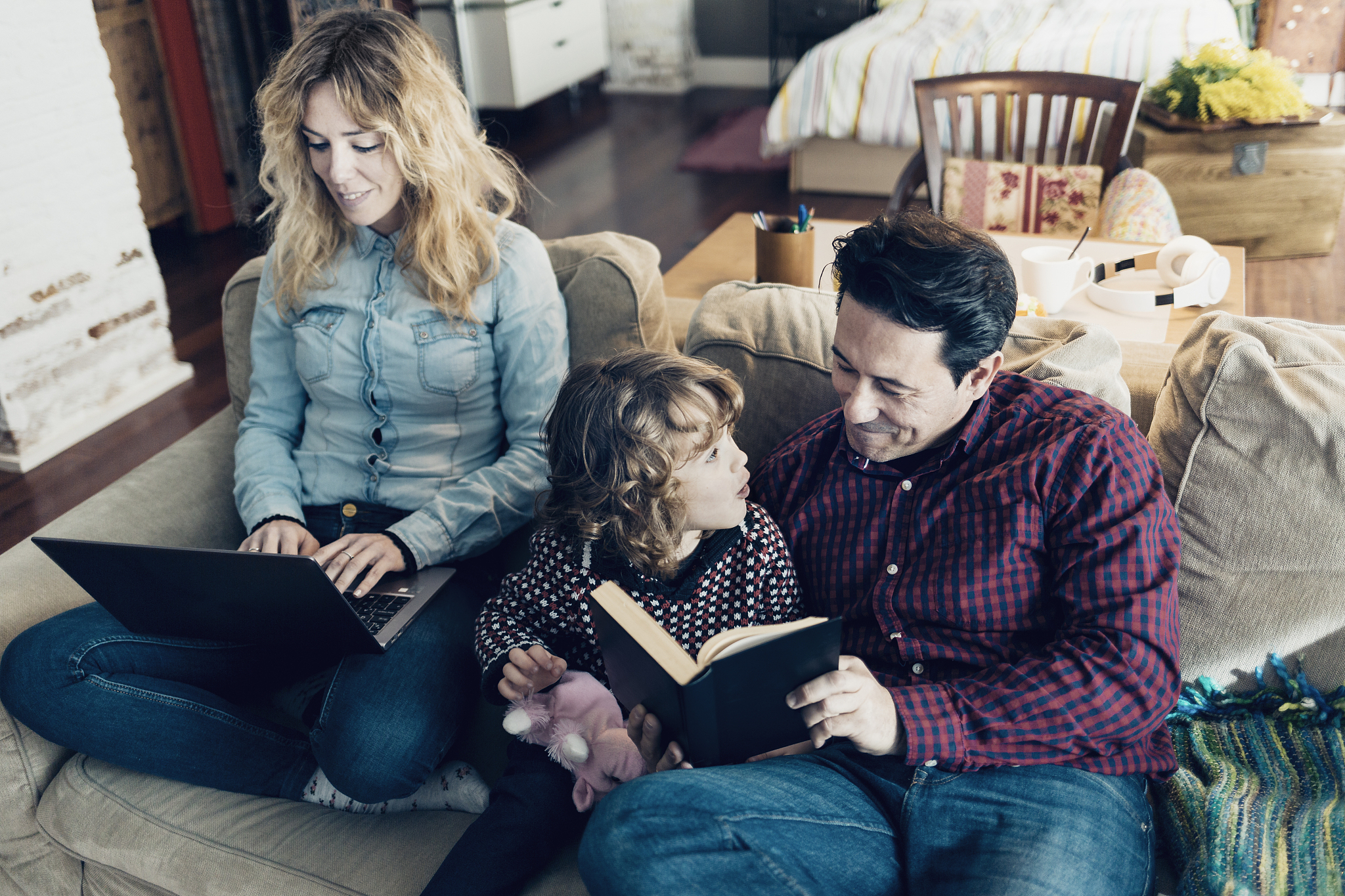 father and his child reading book and mother working