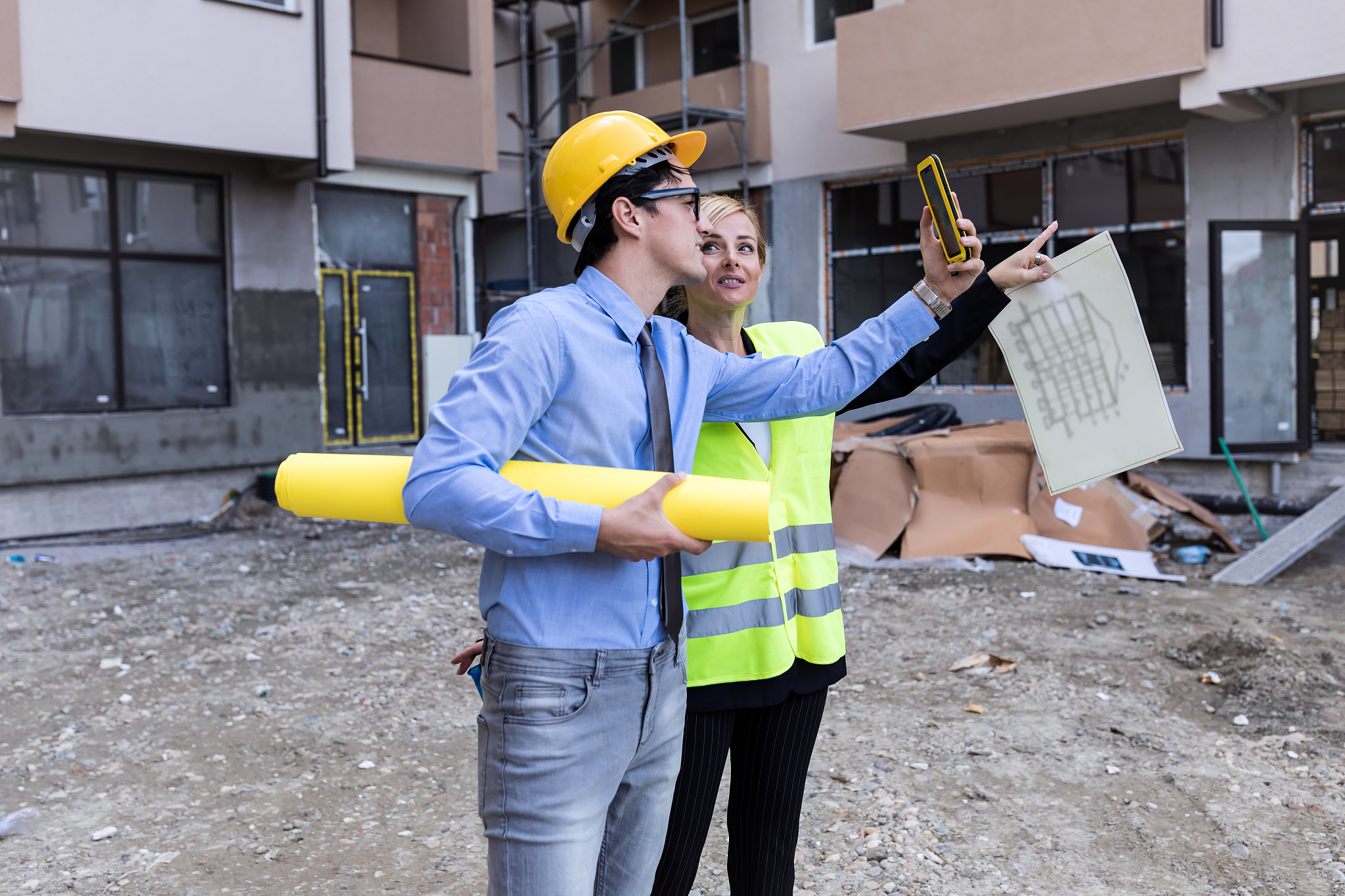 businessman and businesswoman using see plan paper at constructi