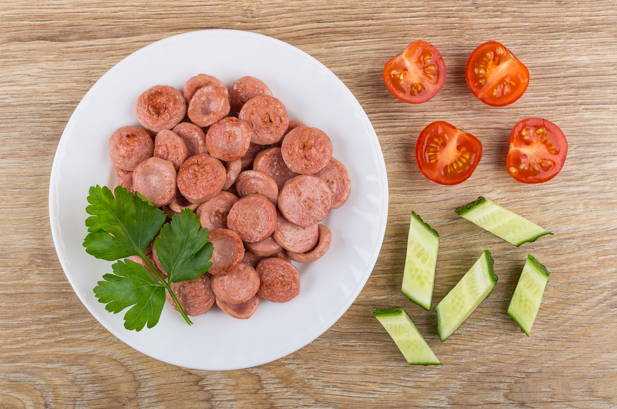 fried sausage, parsley in plate, pieces of tomato and cucumber