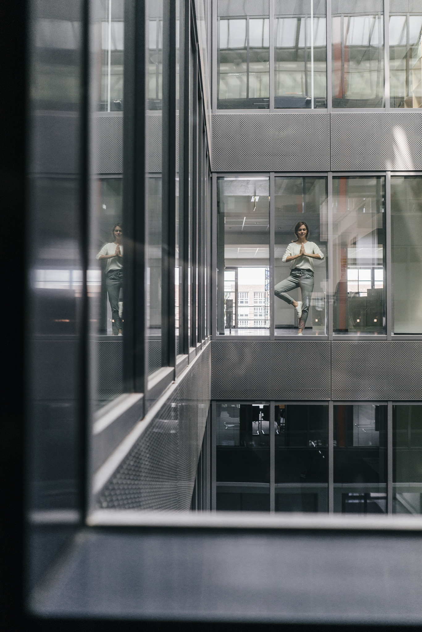 woman standing at office window, practicing yoga