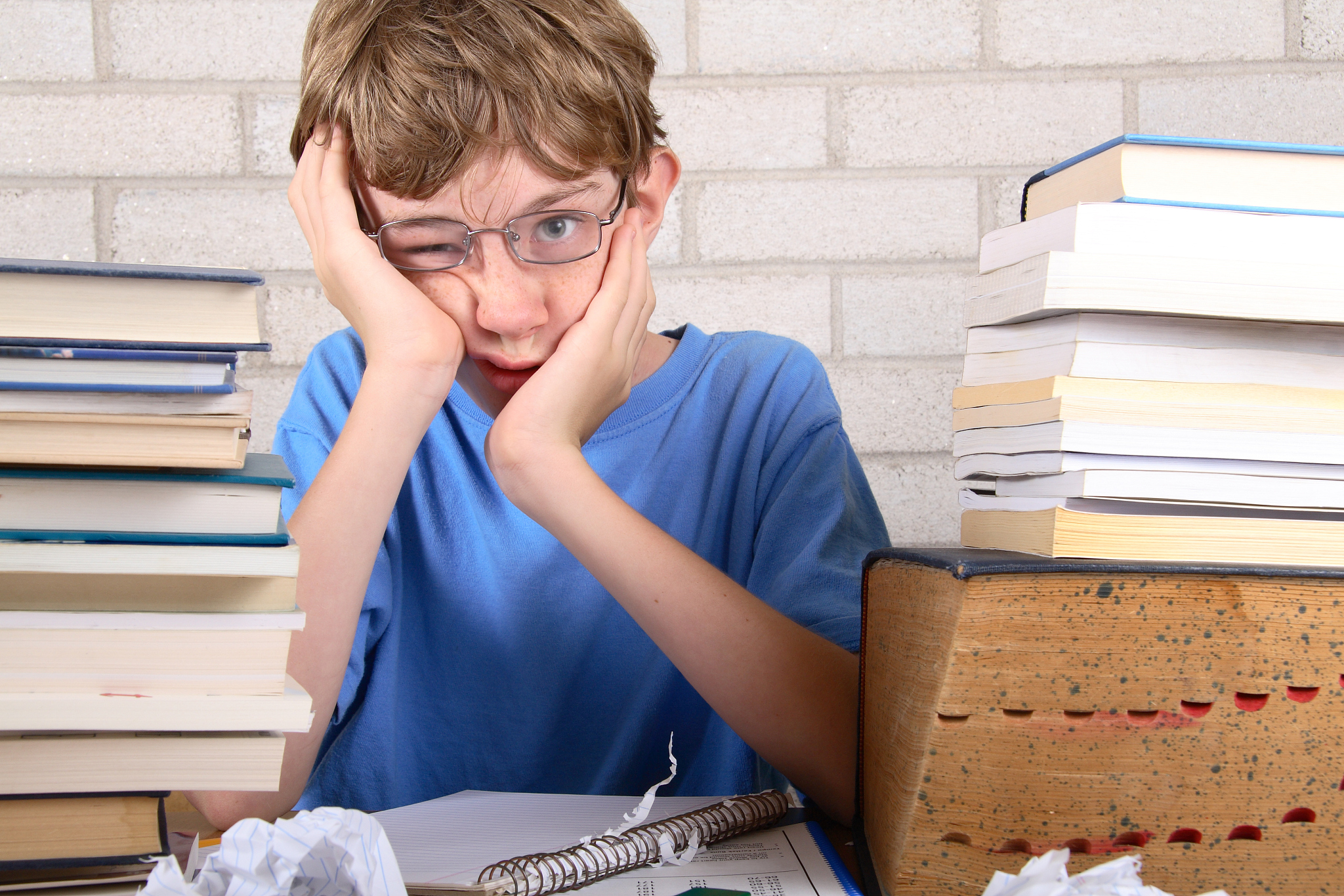 young boy frustrated with stacks of books