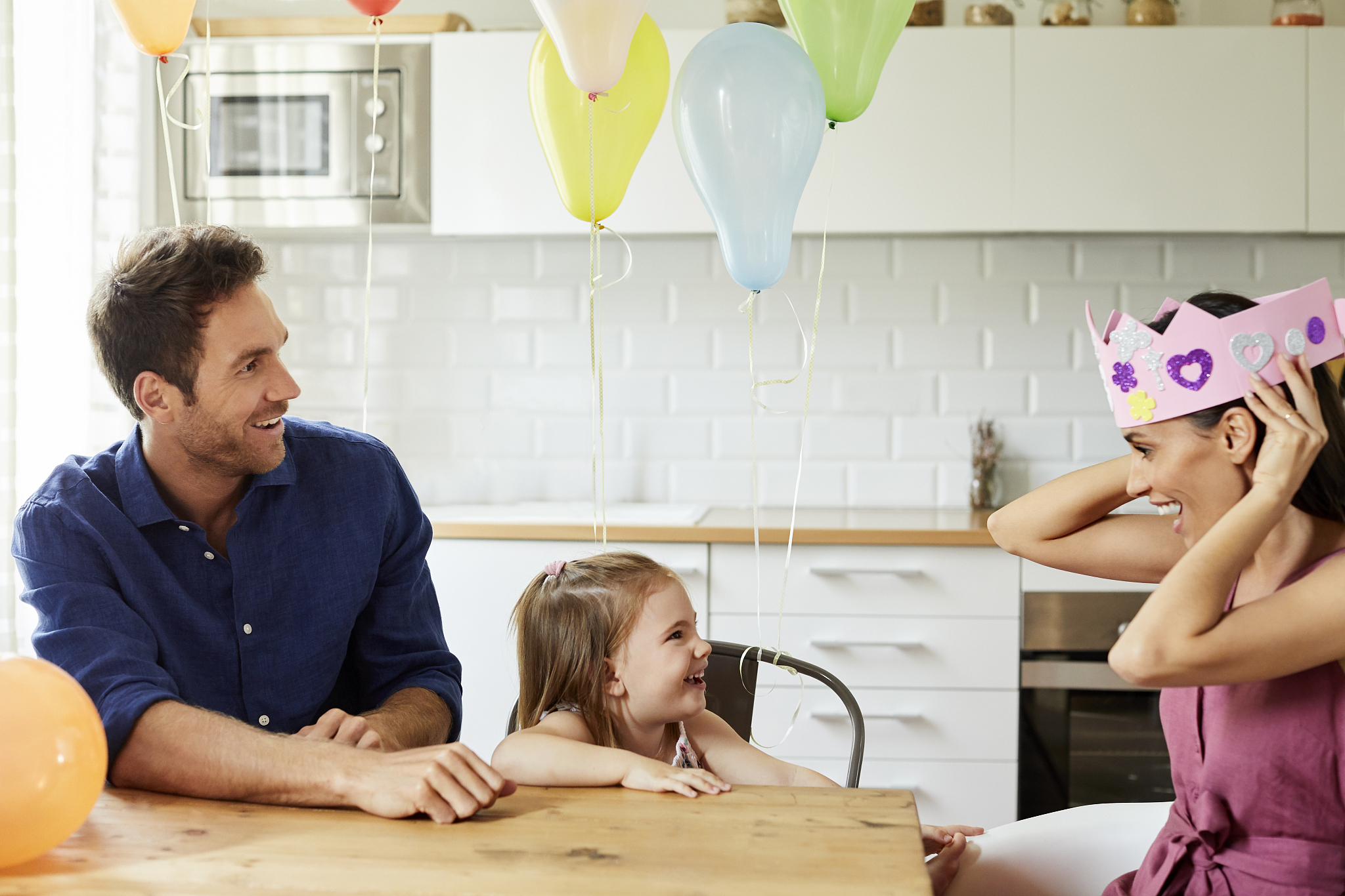 playful woman wearing crown by daughter and man