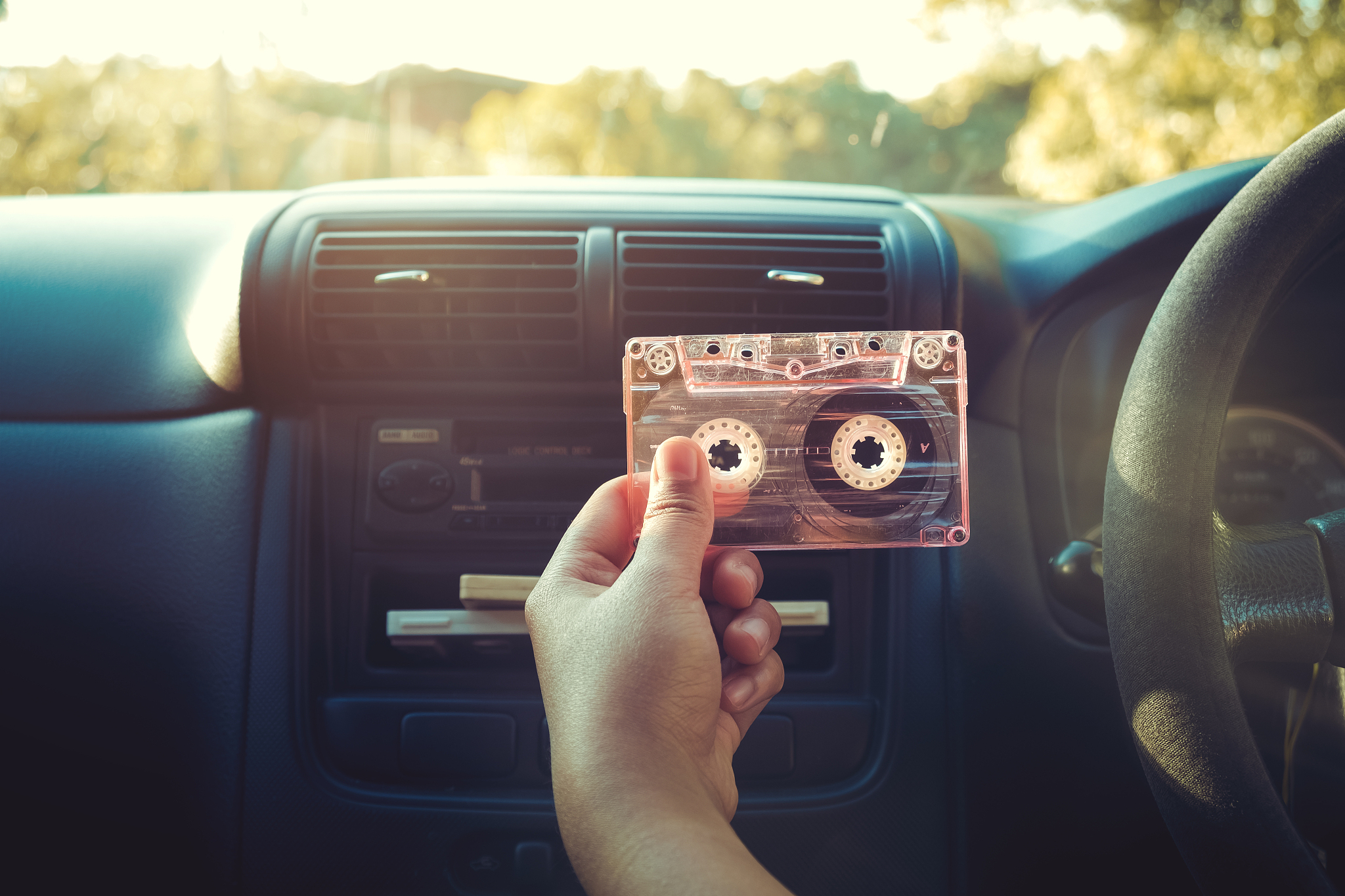 cropped hand of person holding audio cassette in car