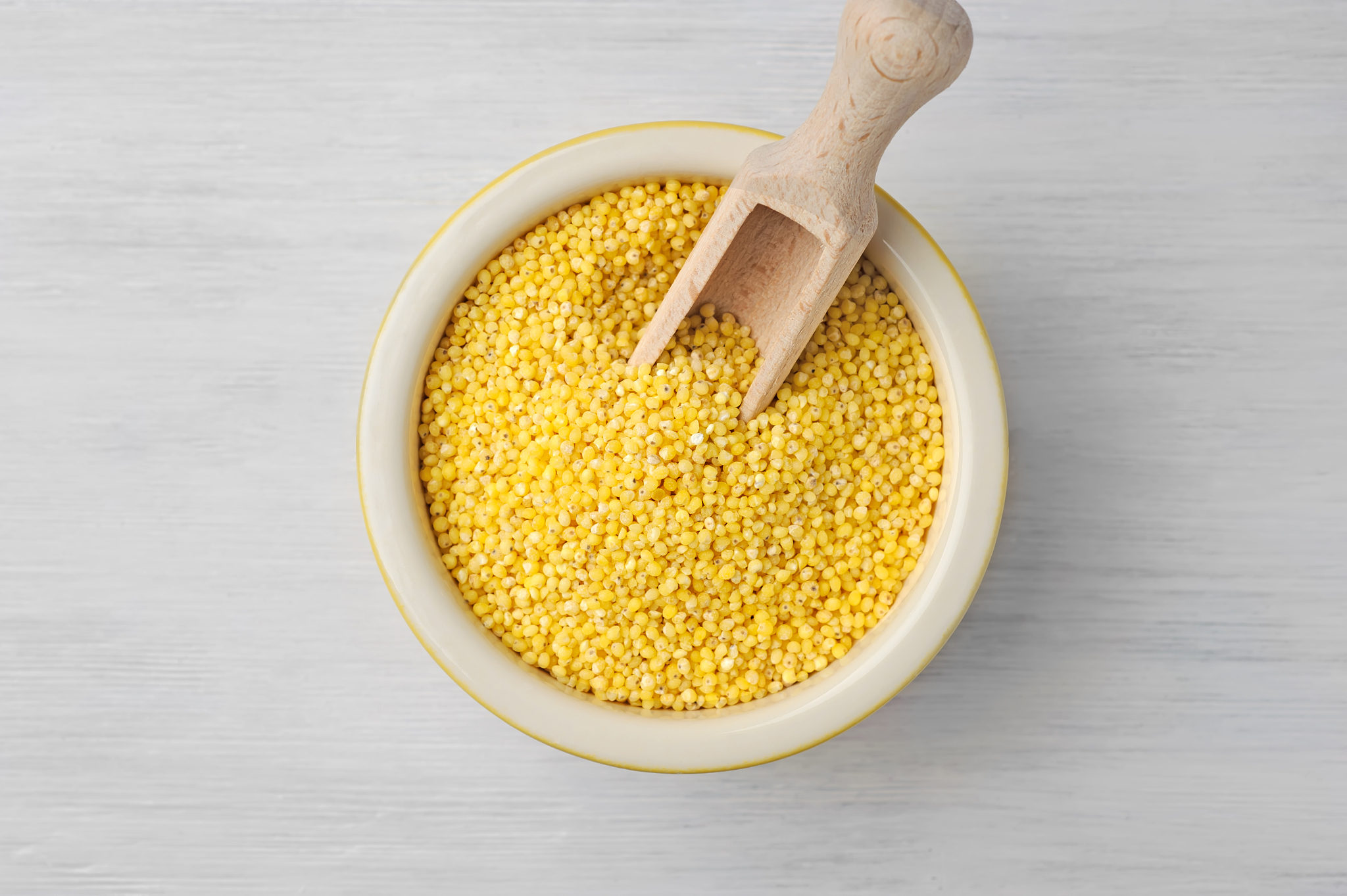 organic millet seeds in a ceramic bowl on wooden white rustic ta