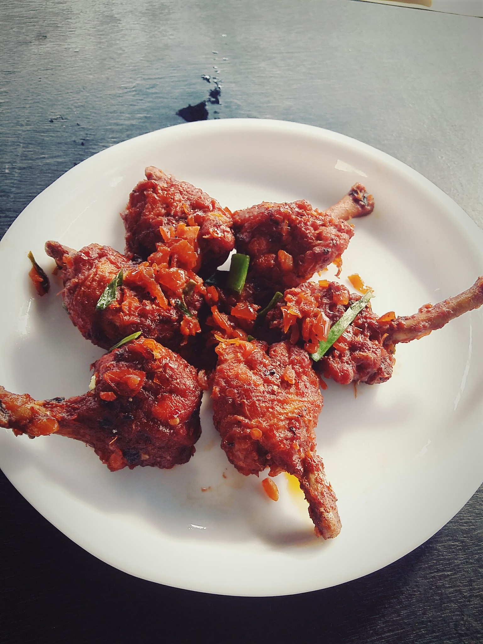 chicken lollipop kept on white plate. wooden table background.