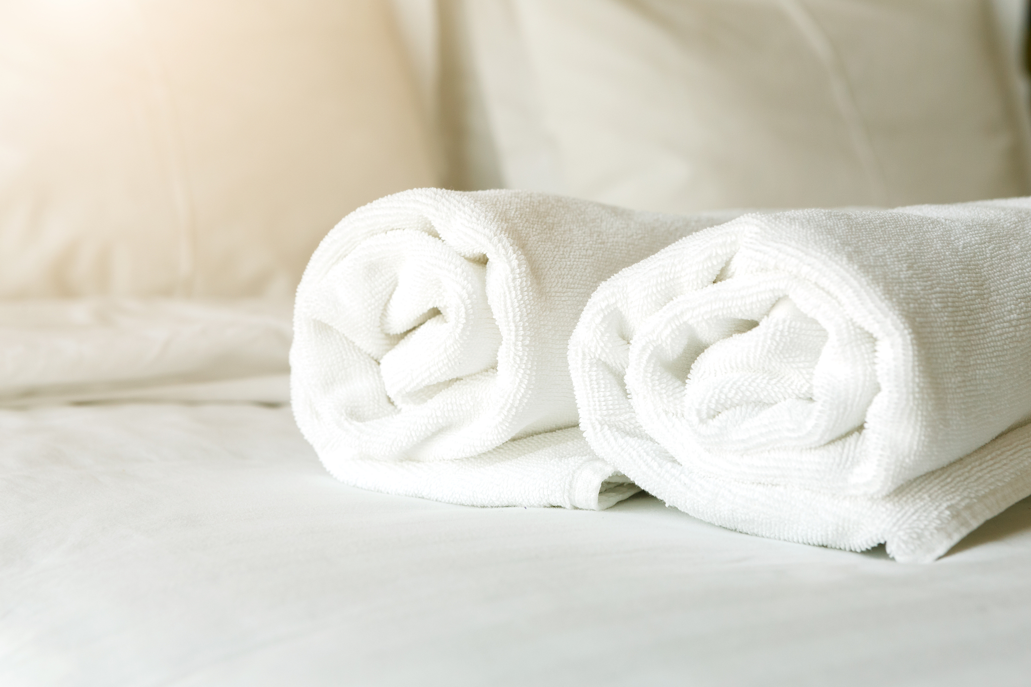 white towels on bed in hotel bedroom closeup