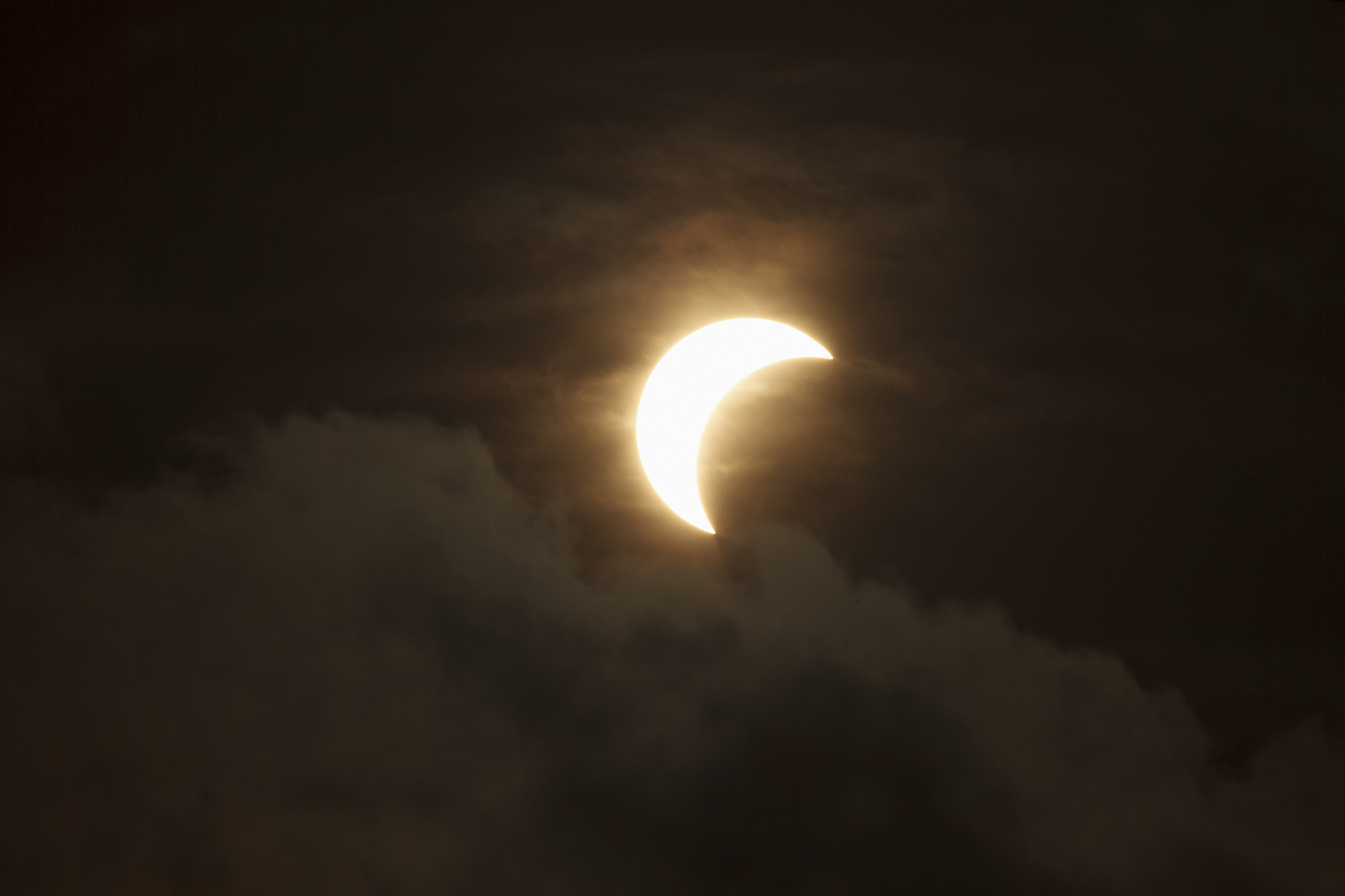 partial solar eclipse through clouds