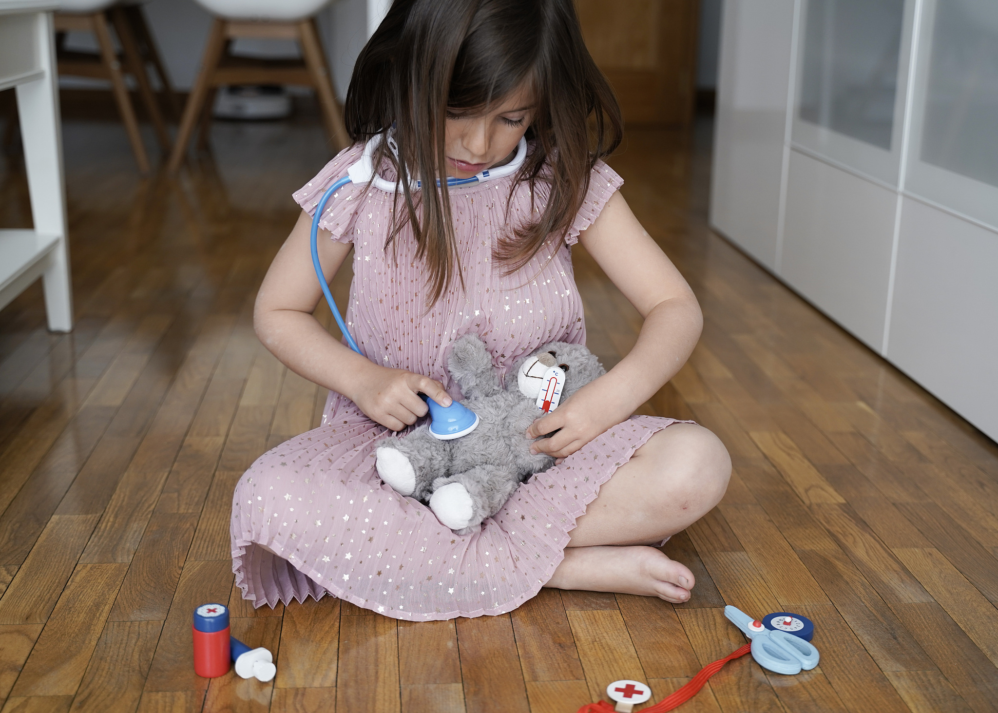 little girl playing doctors with her teddy bear