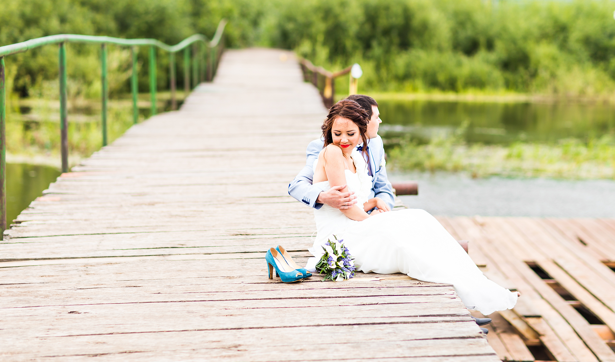 beautiful young wedding couple sitting on the pier