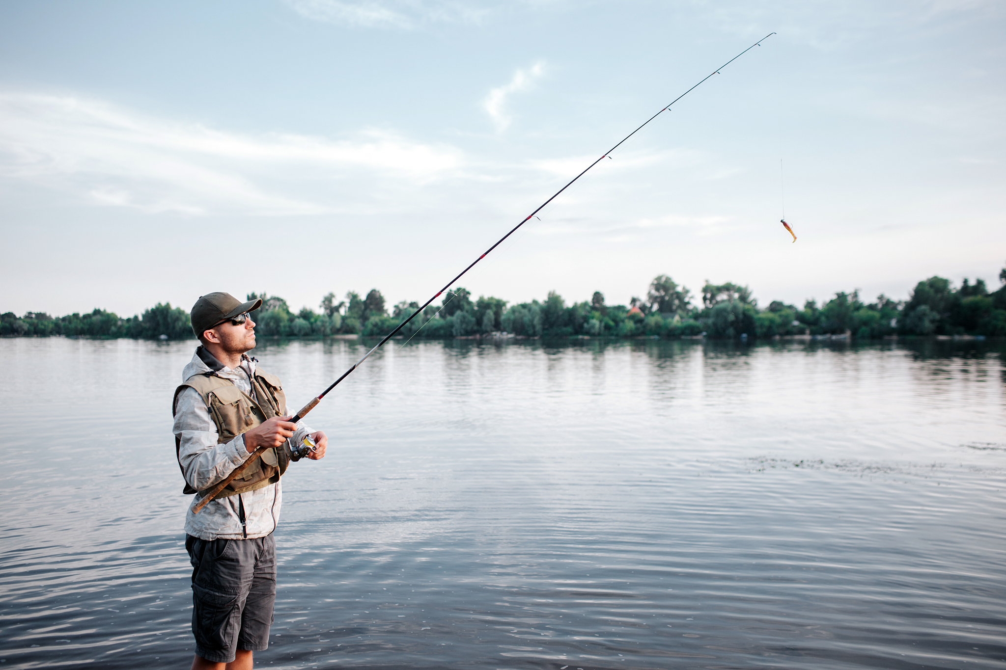 a picture of fishaerman standing in shallow and fishing. he hold
