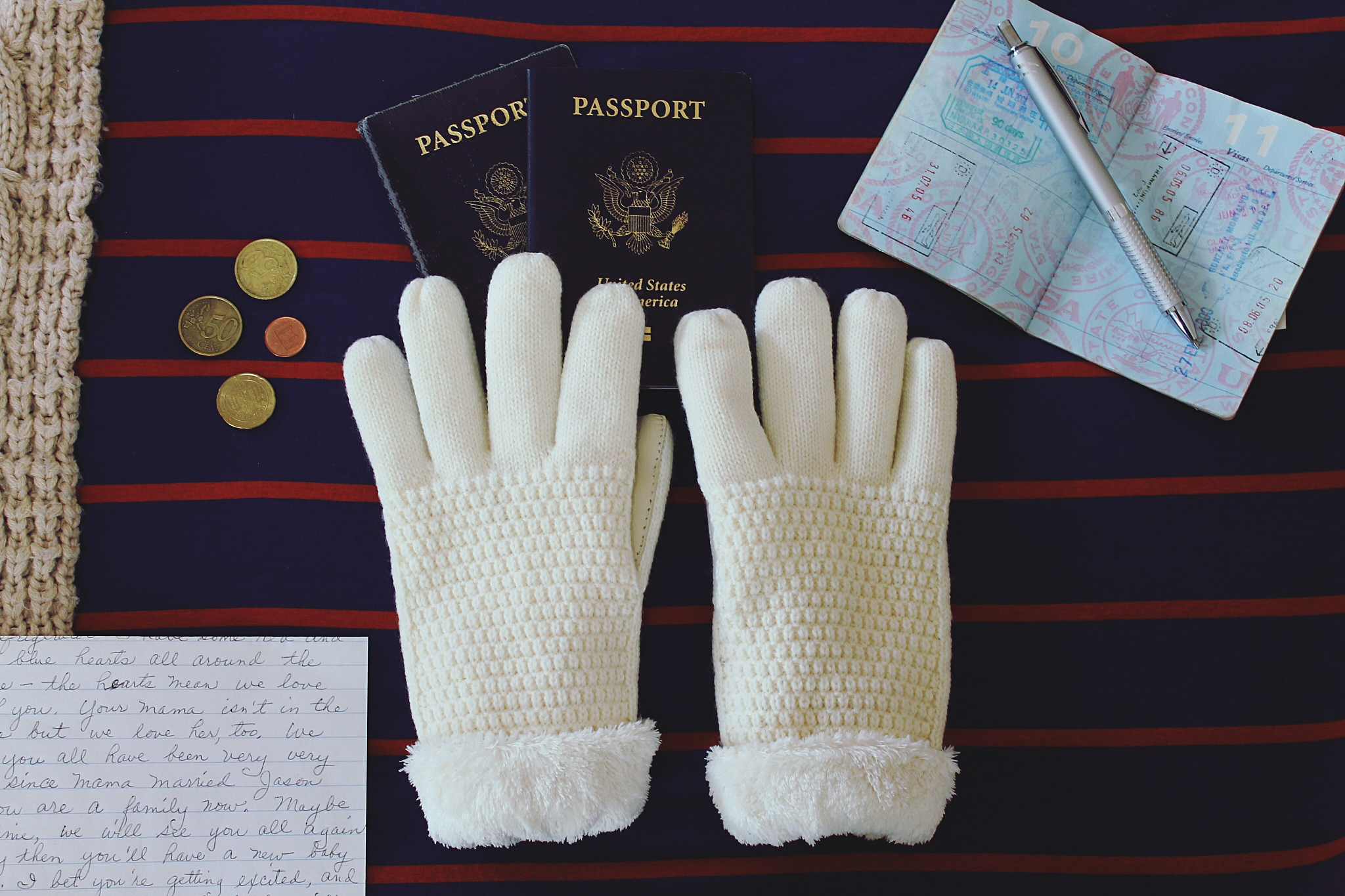 high angle view of gloves by passports and coins on bed