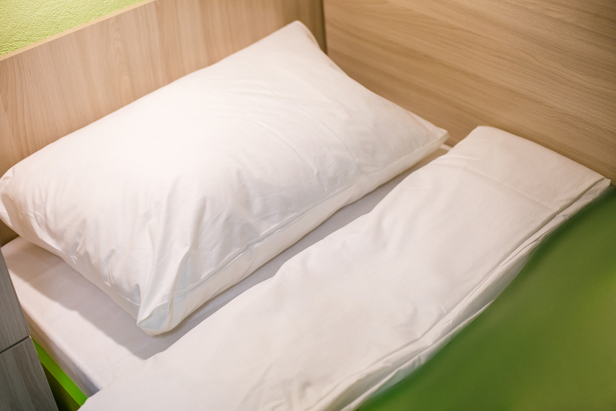 a bed with a white pillow and a green blanket in the cabin of a 
