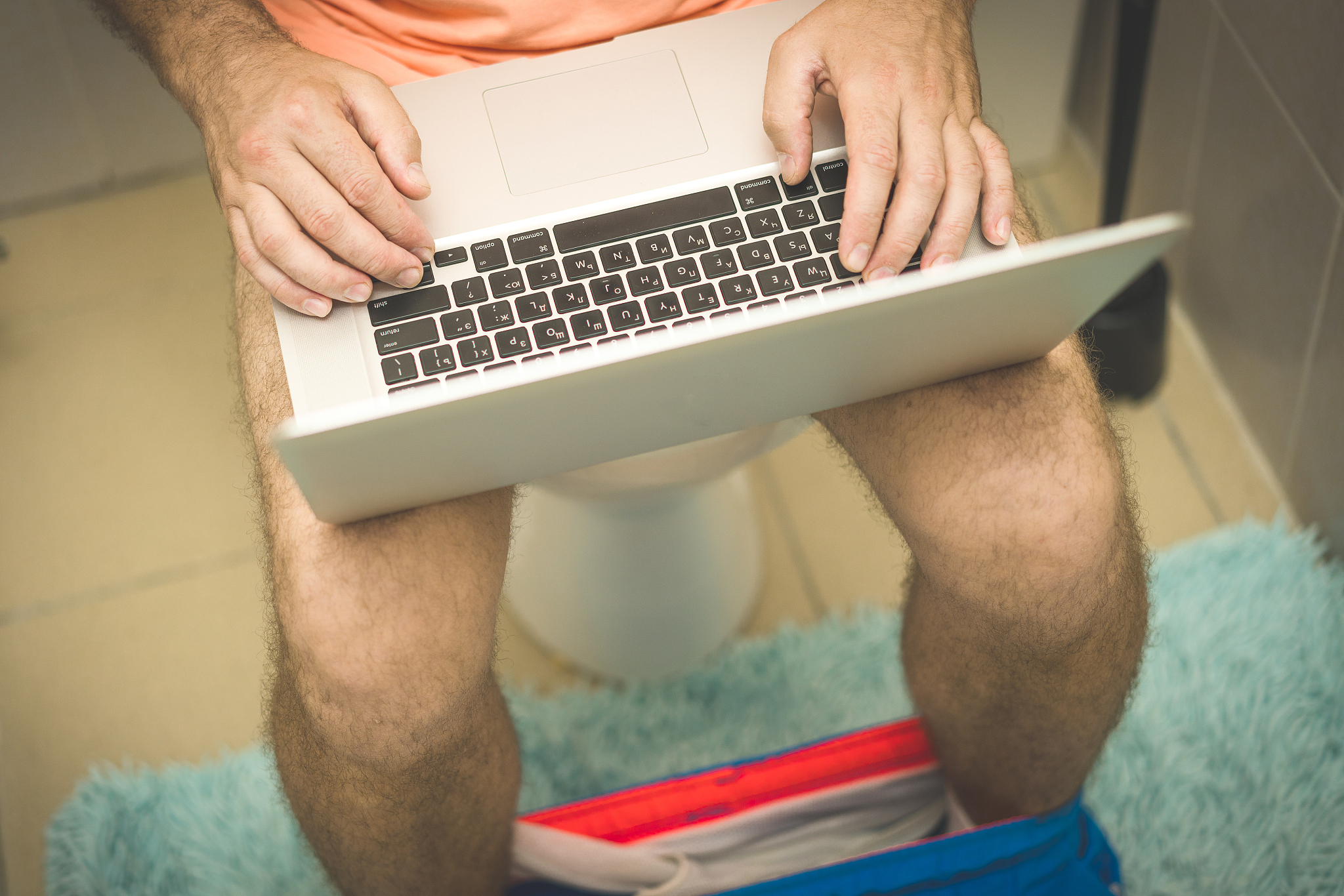 businessman is working with laptop while sitting on the toilet