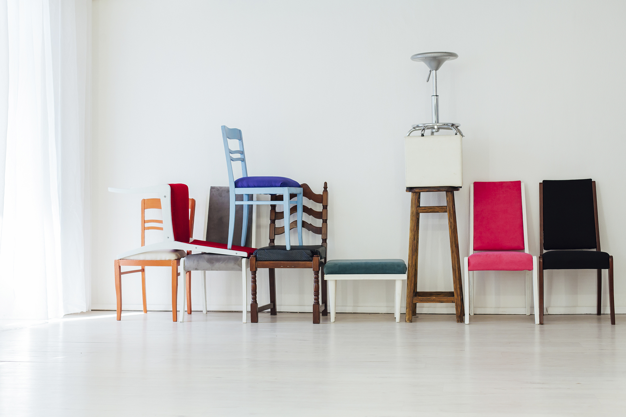 many different chairs stand in the white room