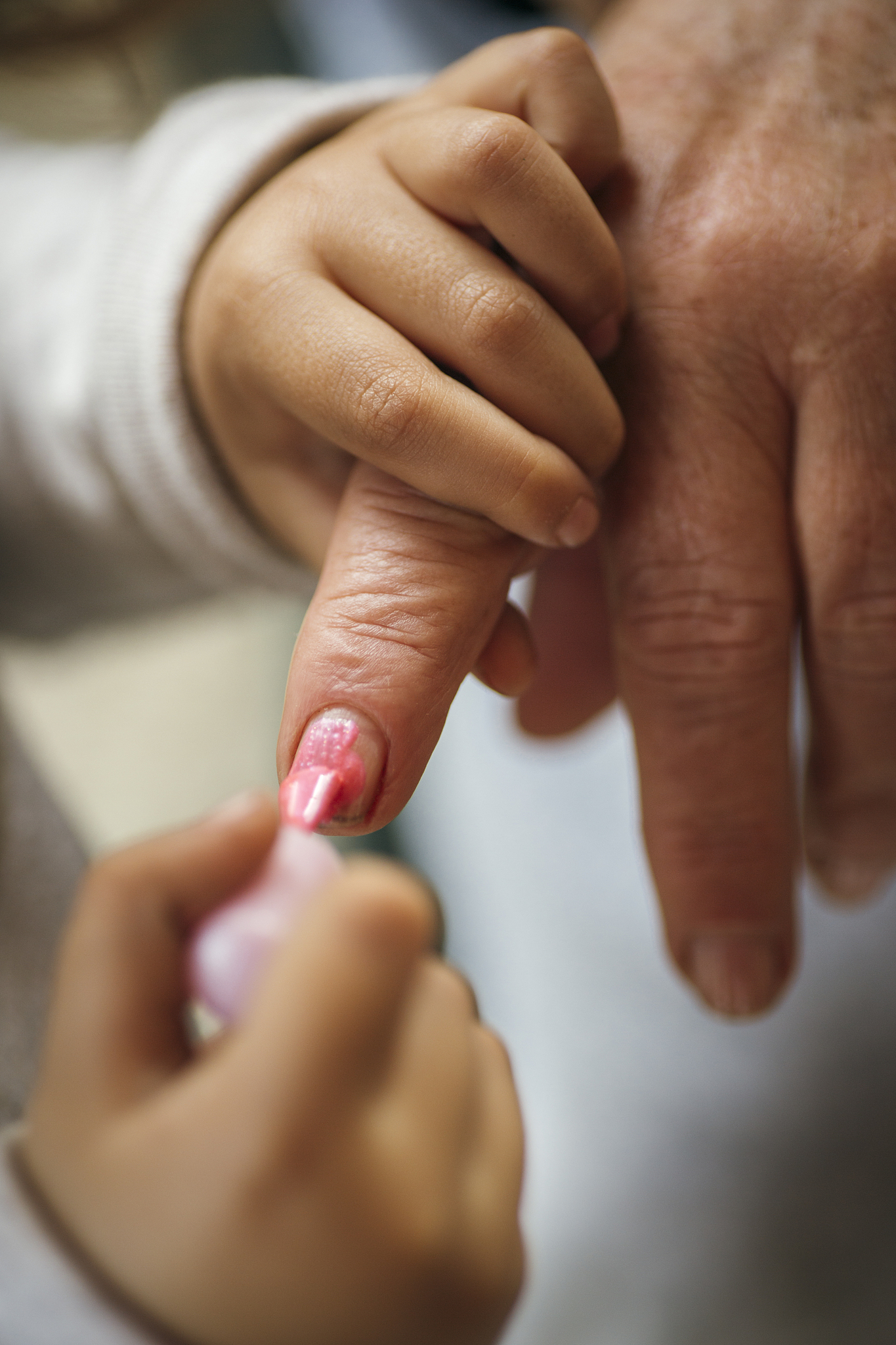 little girl painting her grandmother's finger nails