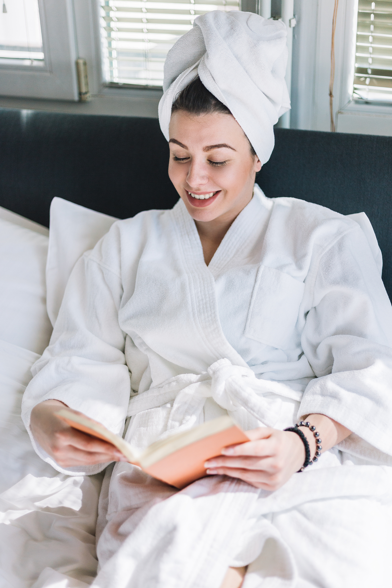 young woman lying on the bed, reading a book