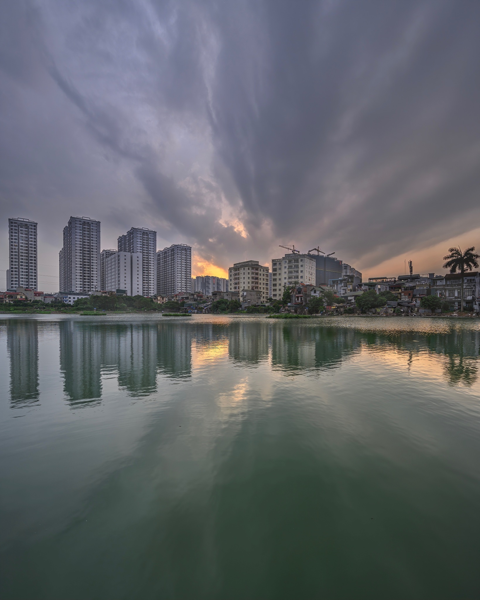 buildings by river against sky in city