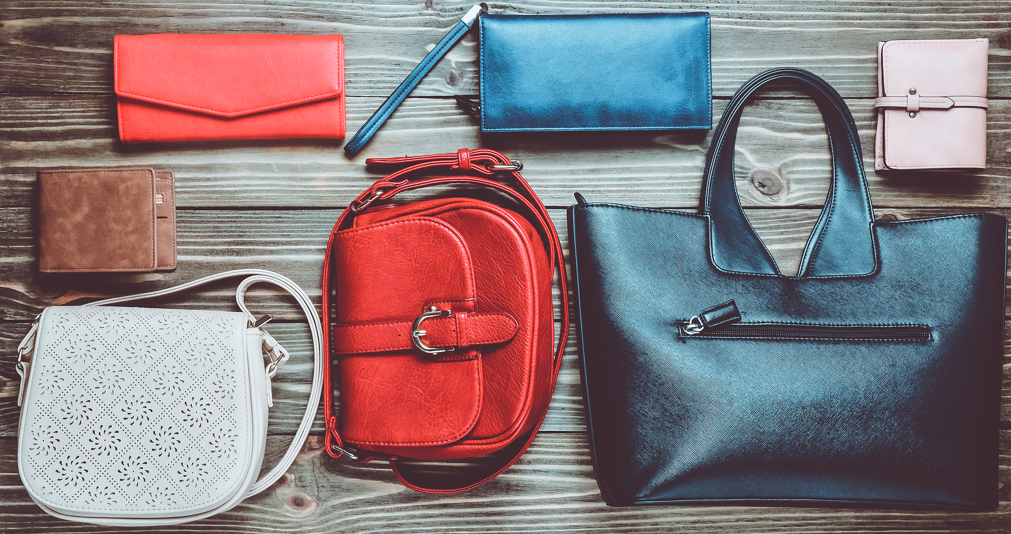 many women's bags and purses on a wooden background. top view.