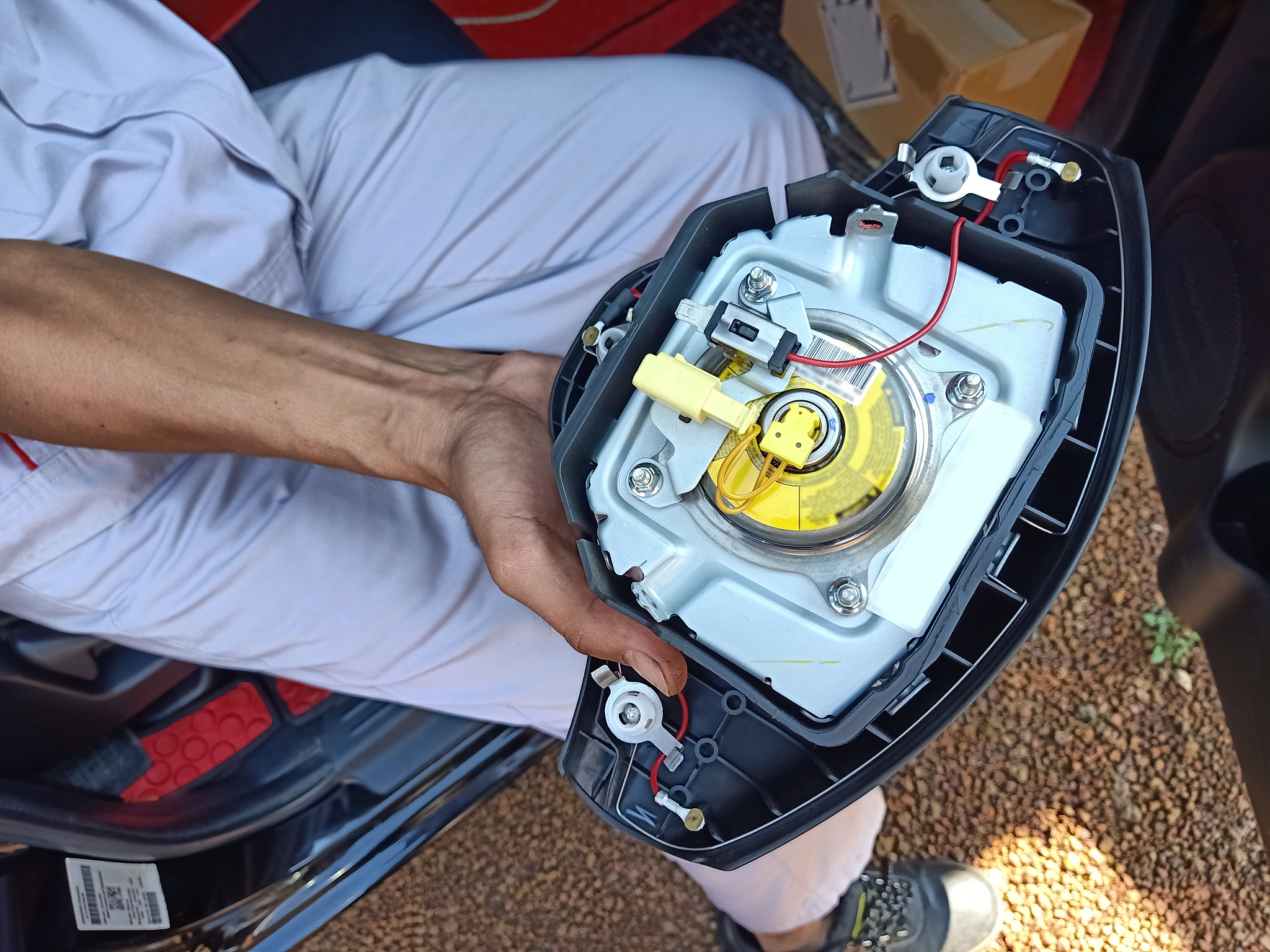 the technician in uniform holding the airbag panel that take off