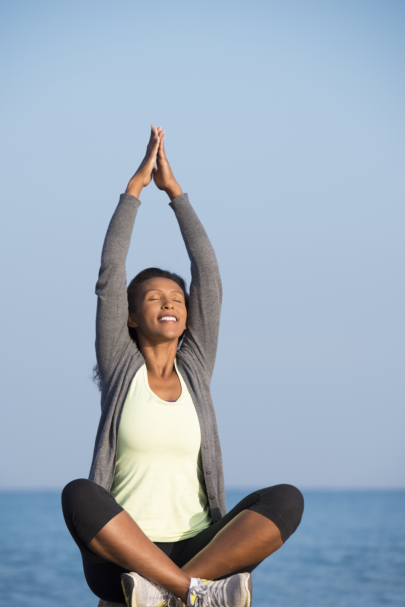 woman practicing yoga, sitting in yoga position outdoors.