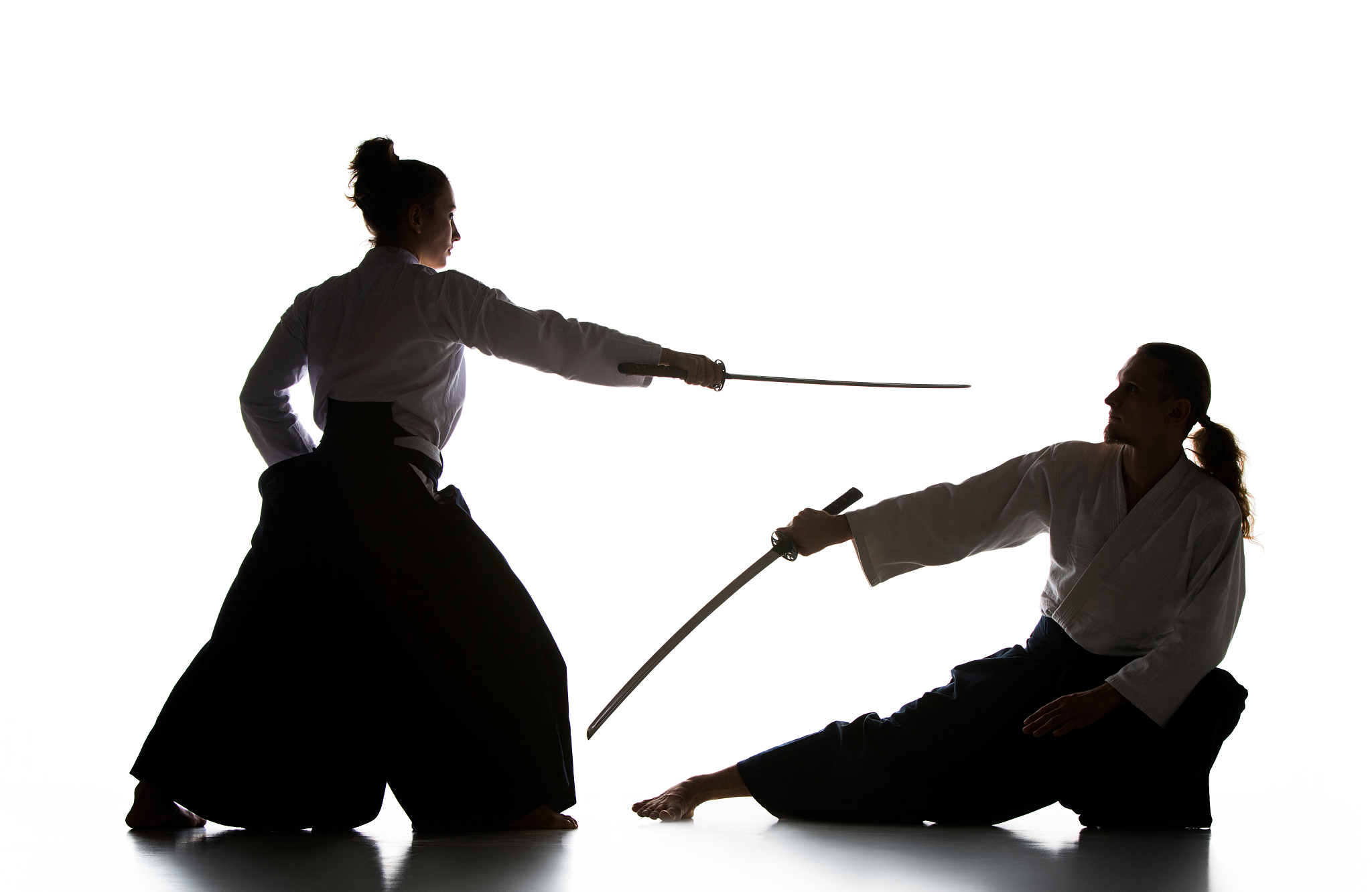 man and woman fighting and training aikido on white studio backg