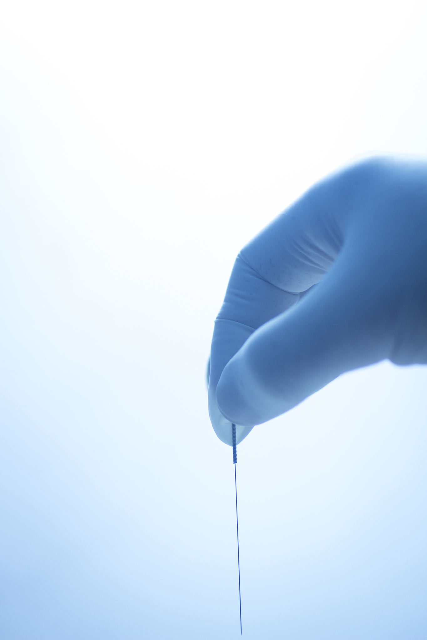 cropped hand holding acupuncture needle in hospital