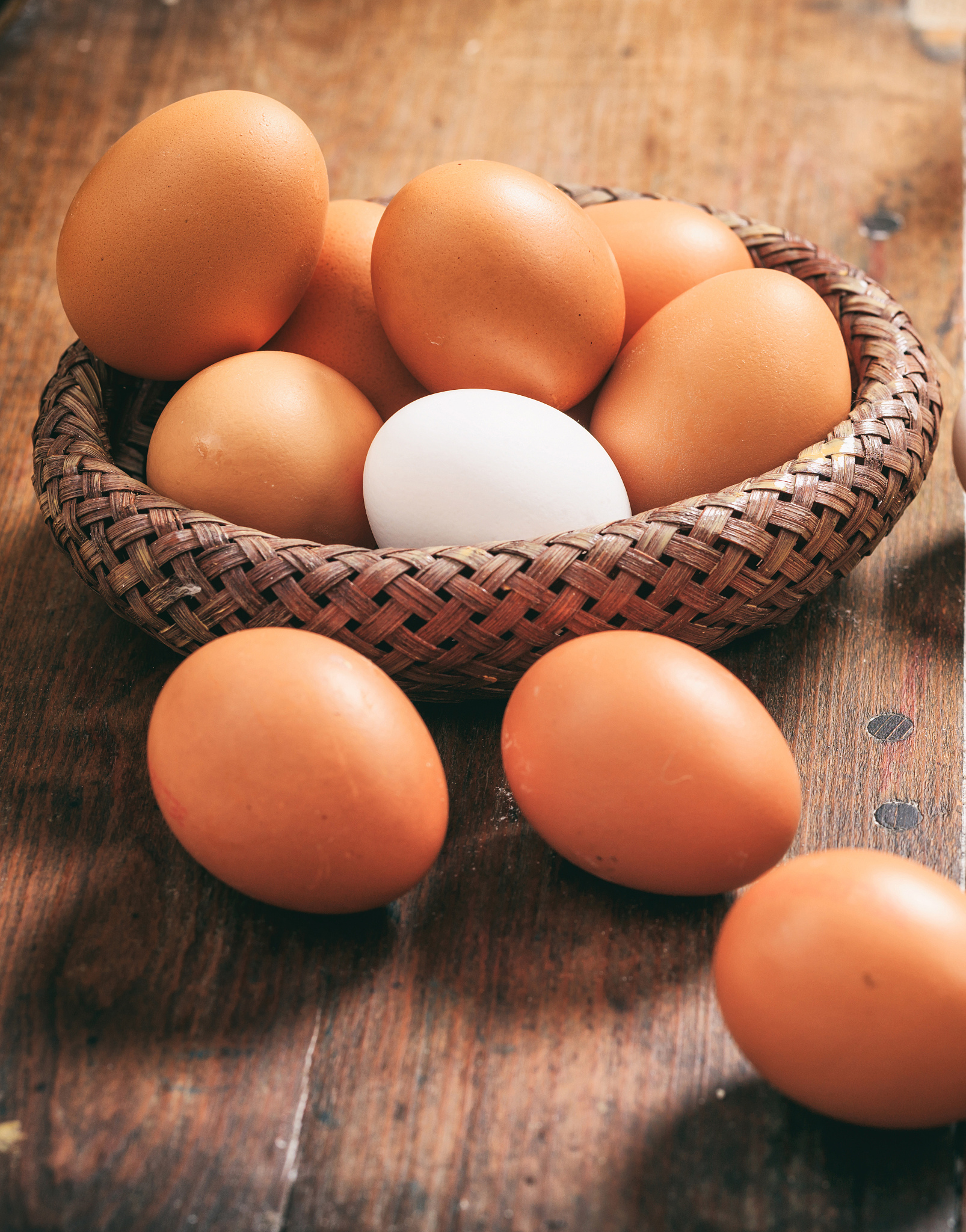 chicken eggs in a basket on wood, closeup vertical view