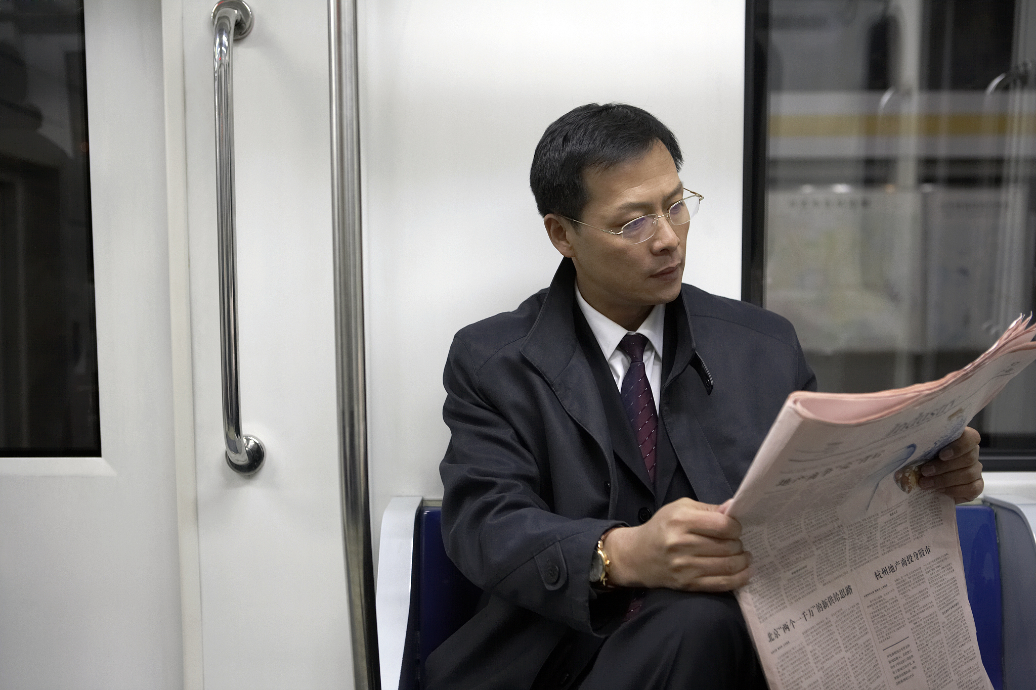 商务男士在地铁里看报纸