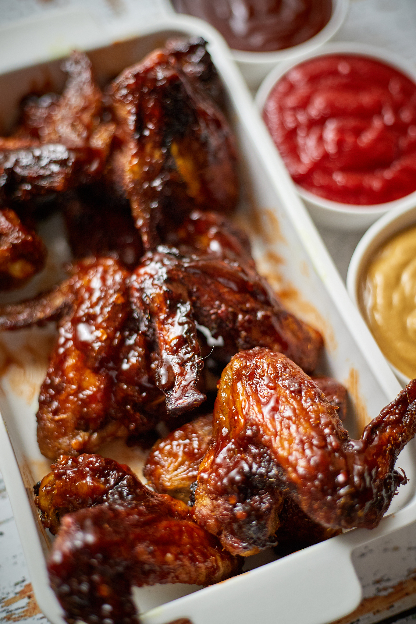 chicken wings in thick barbecue sauce with various side dips. se