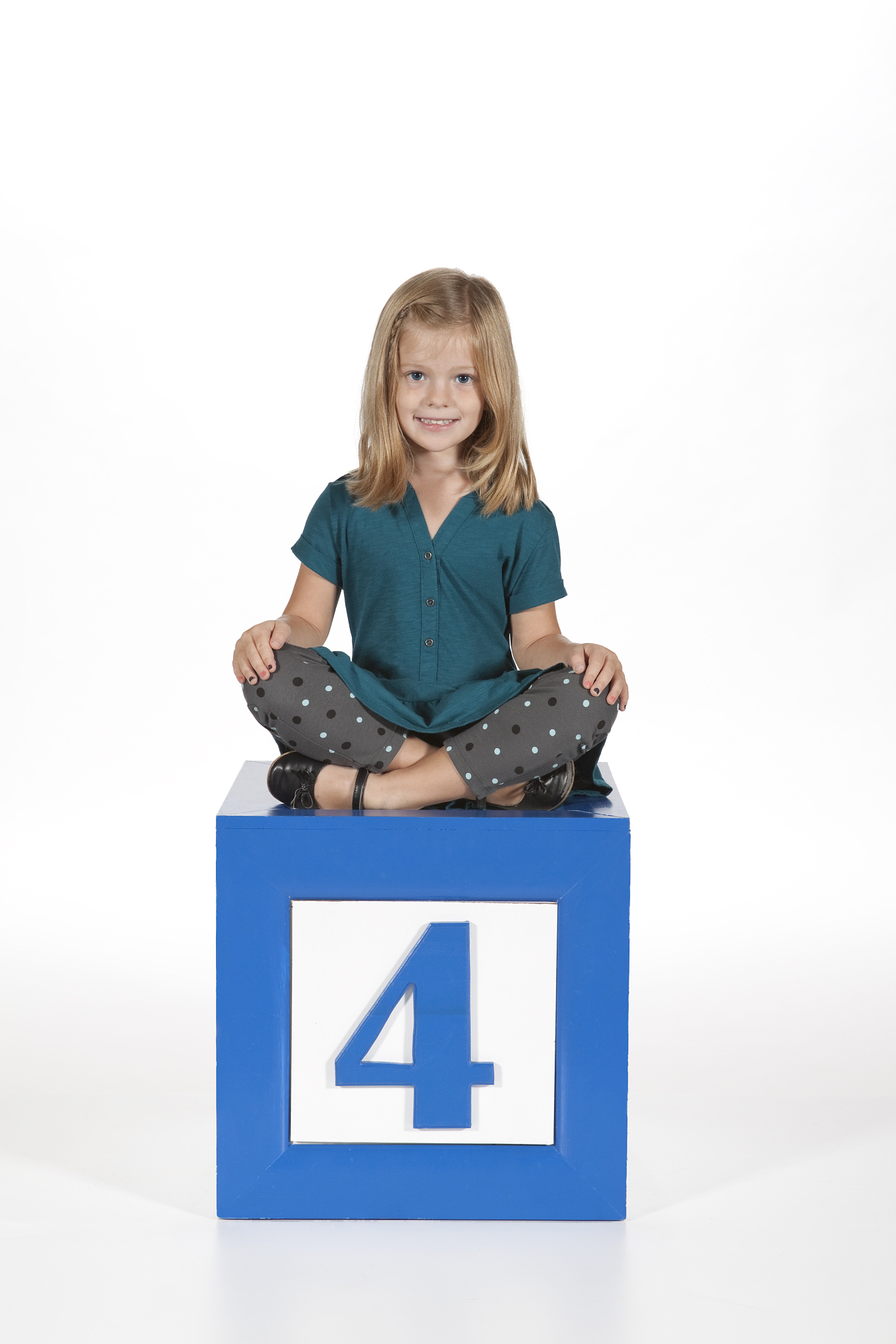 four year old girl sitting on number block, white background