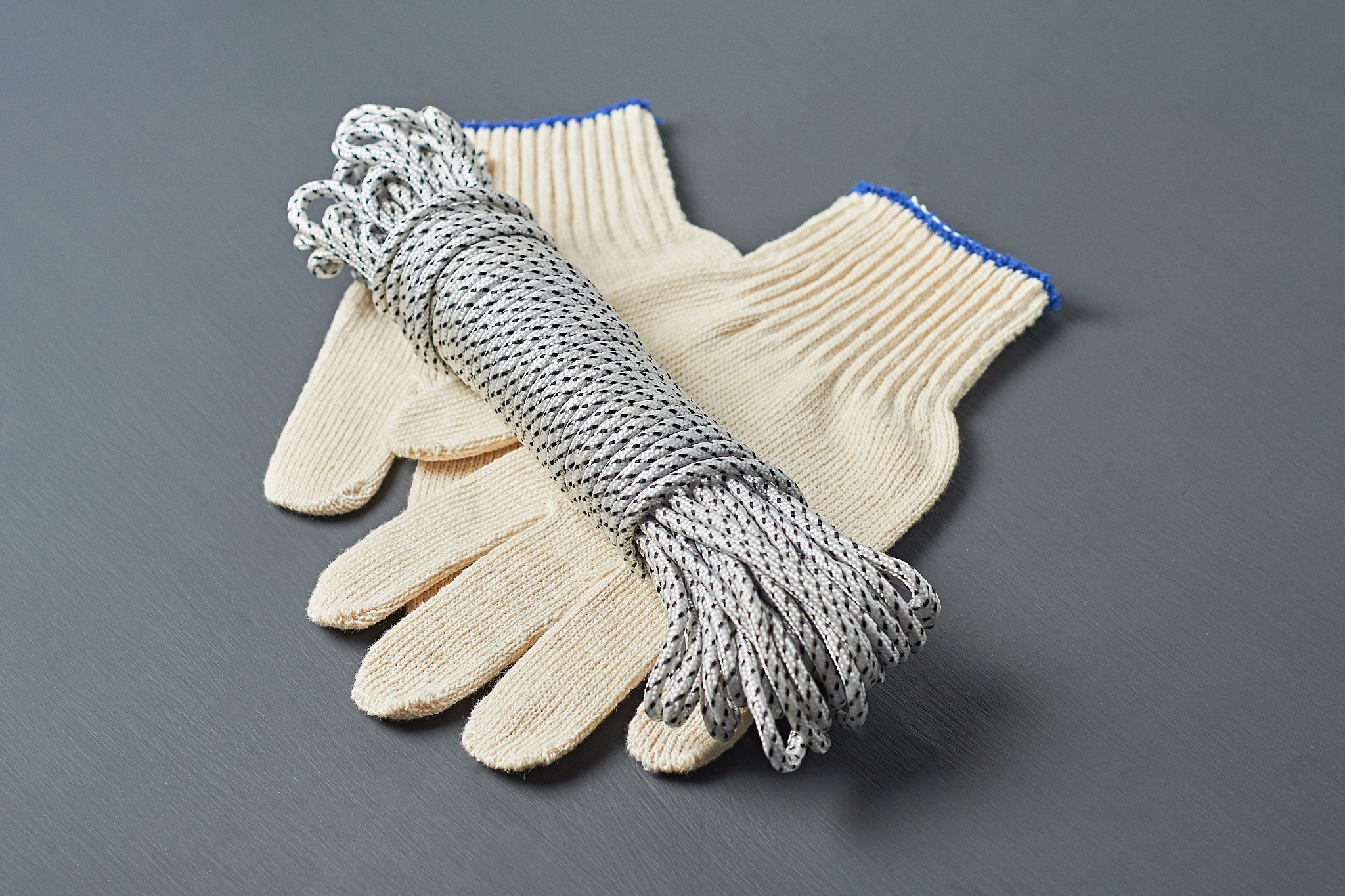 bundle of black and white strong rope beside textile gloves lies