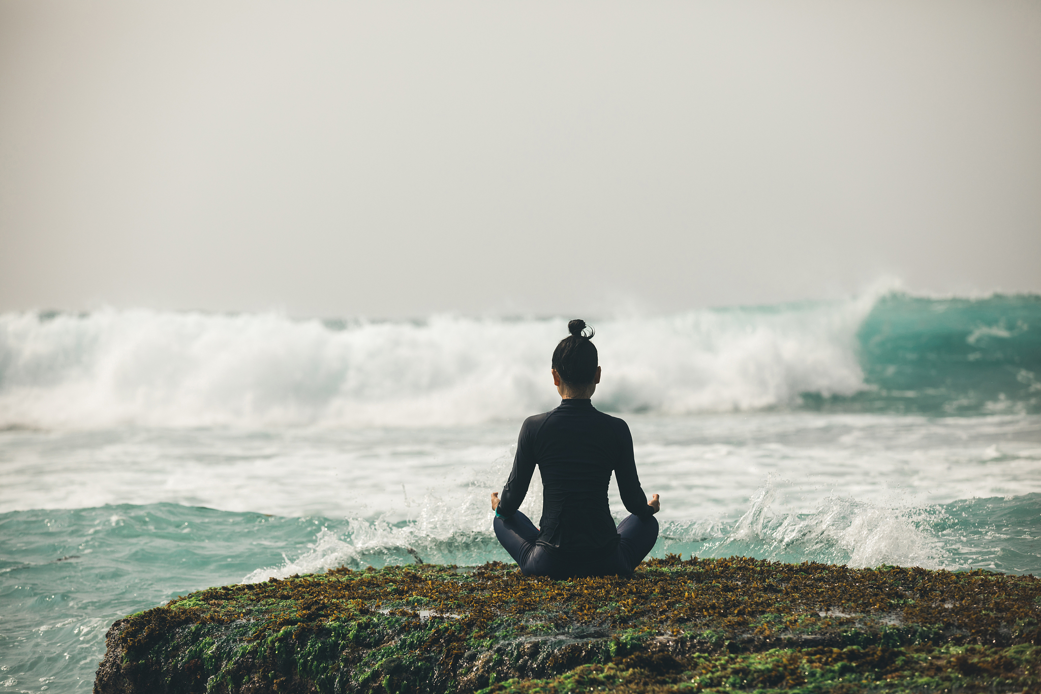 yoga woman meditation at the seaside cliff edge facing the comin
