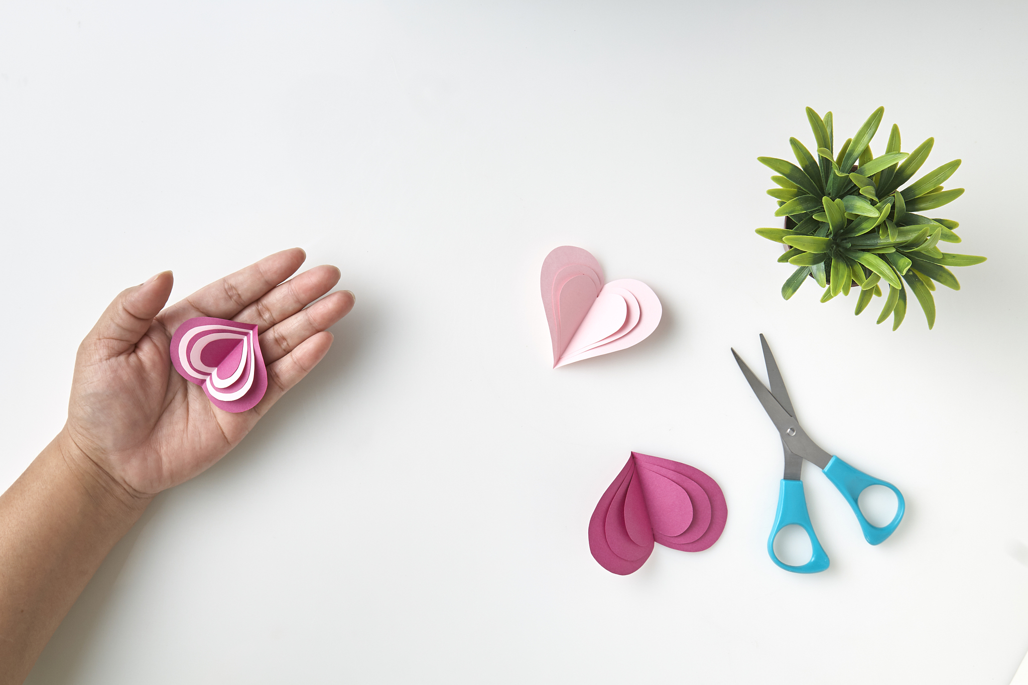 cropped hand making paper heart shape on white background