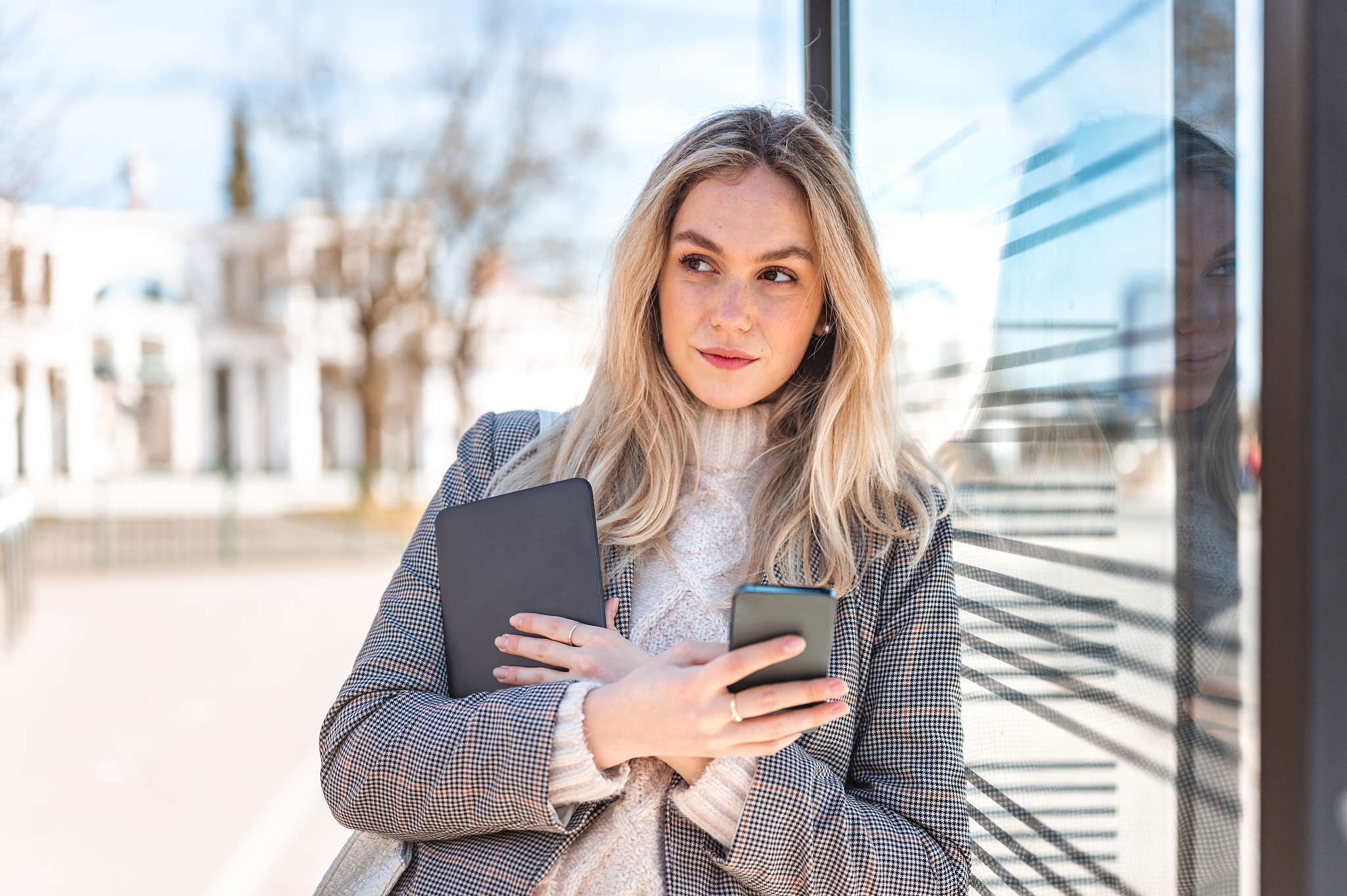 young woman using a mobile phone and a digital tablet outdoors s