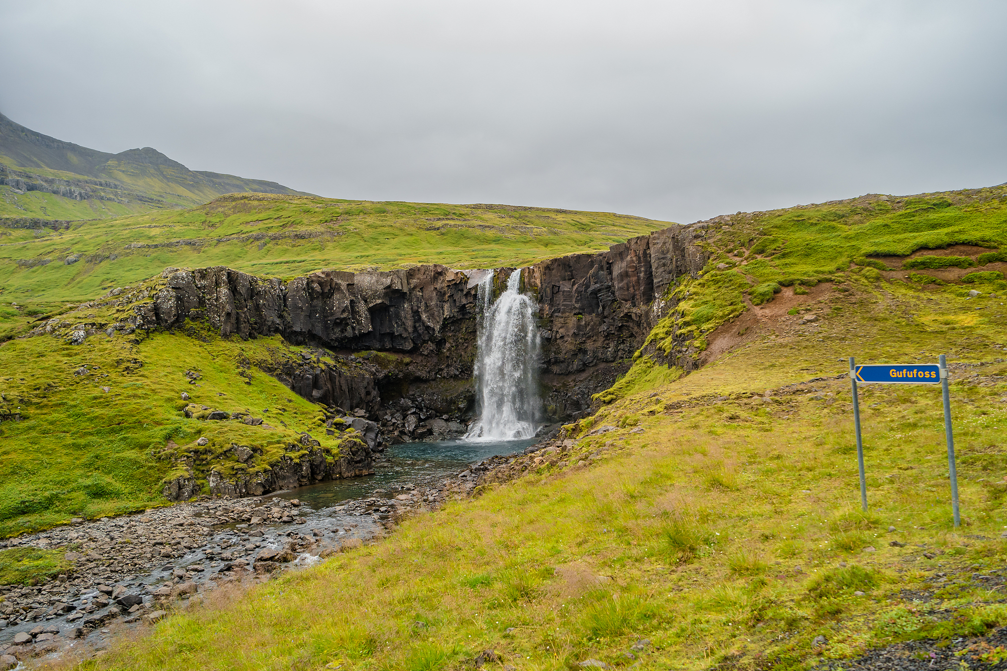 lonely waterfall called gufufoss near the road with a sign spelt