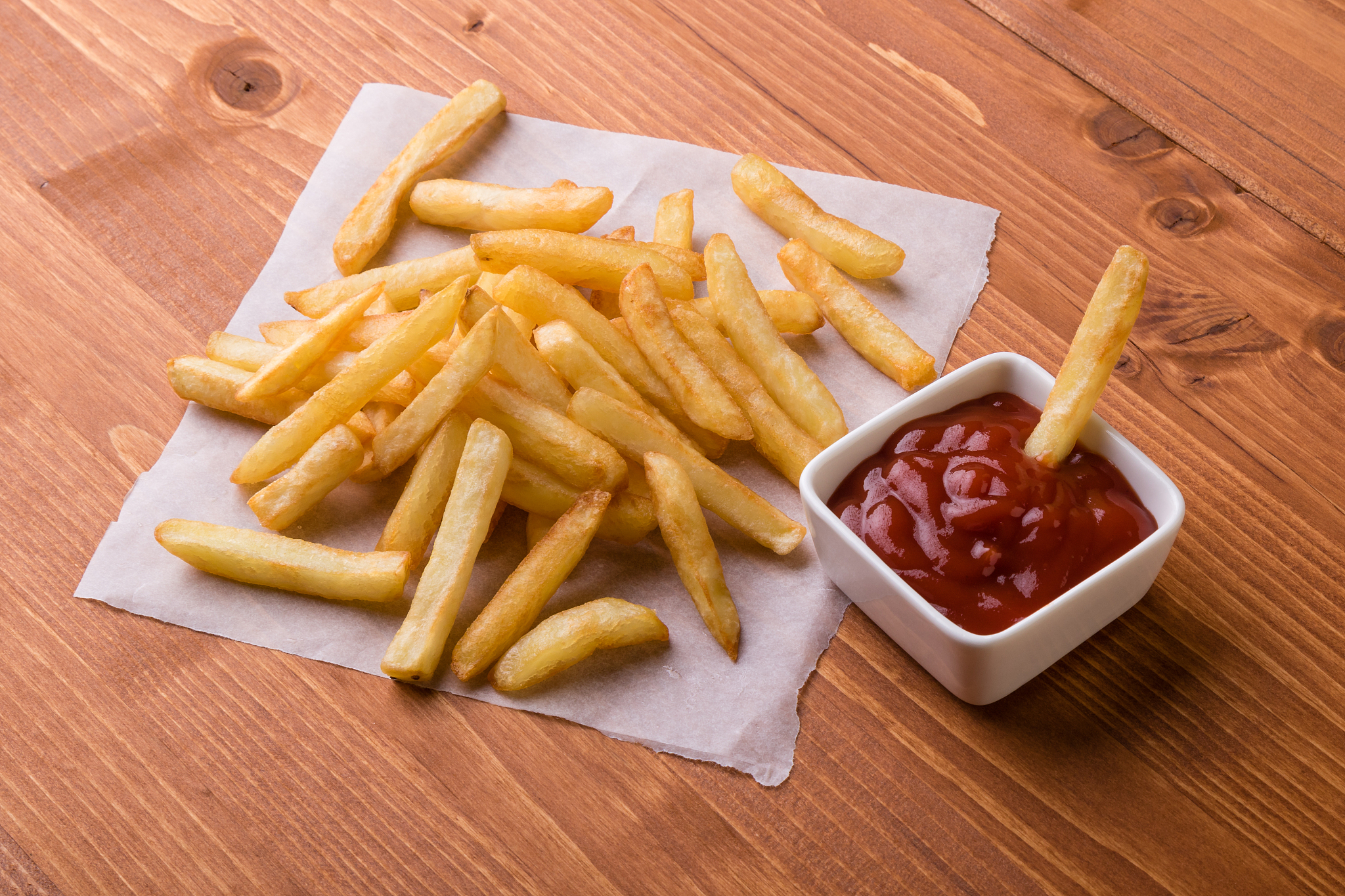 fries on a wooden table with ketchup
