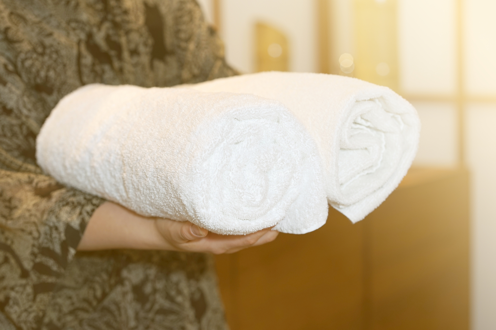 the woman is holding a rolled towel.