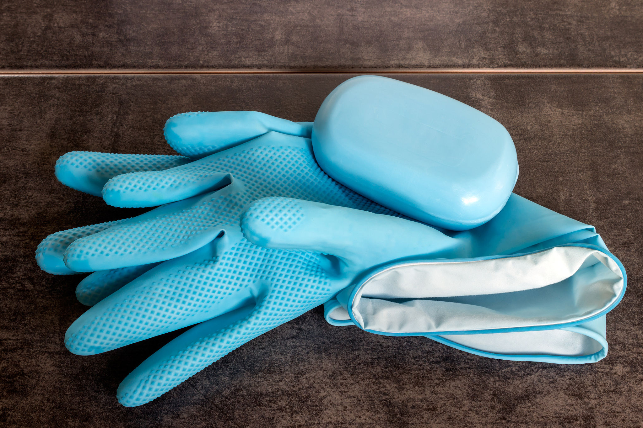 blue rubber gloves and soap on a dark background. concept - clea