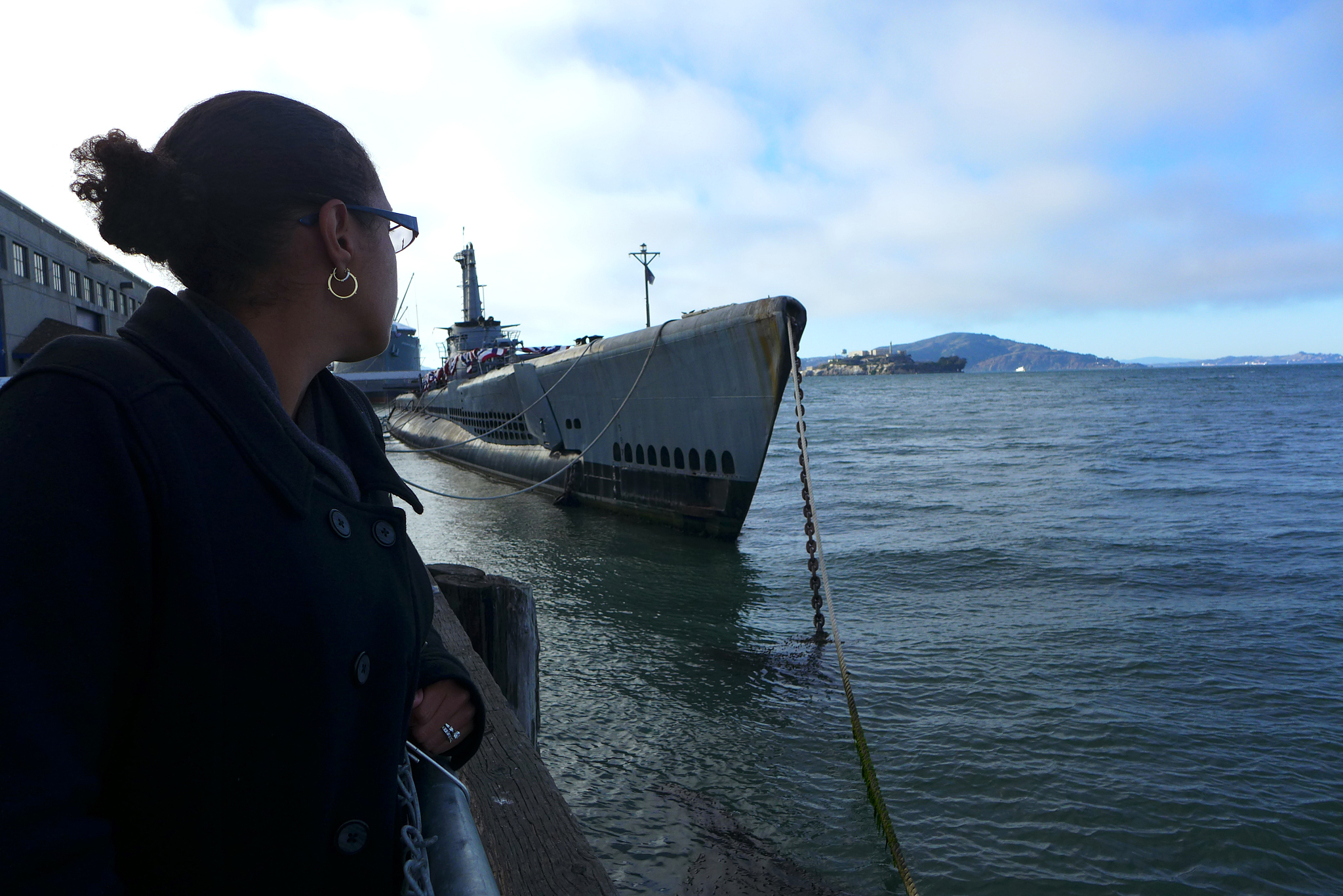 submarine docked at a pier with a lady looking