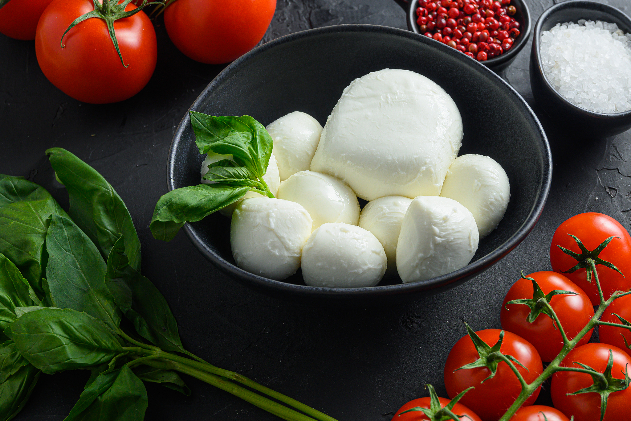 mozzarella balls, in black bowl.