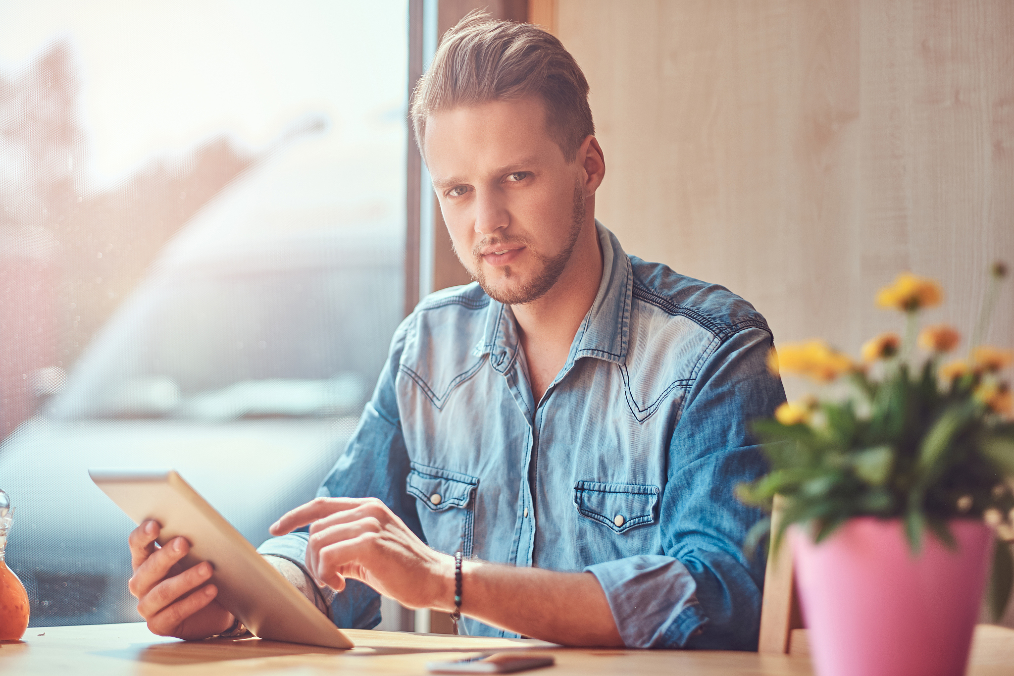 hipster guy with a stylish haircut and beard sits at a table in 