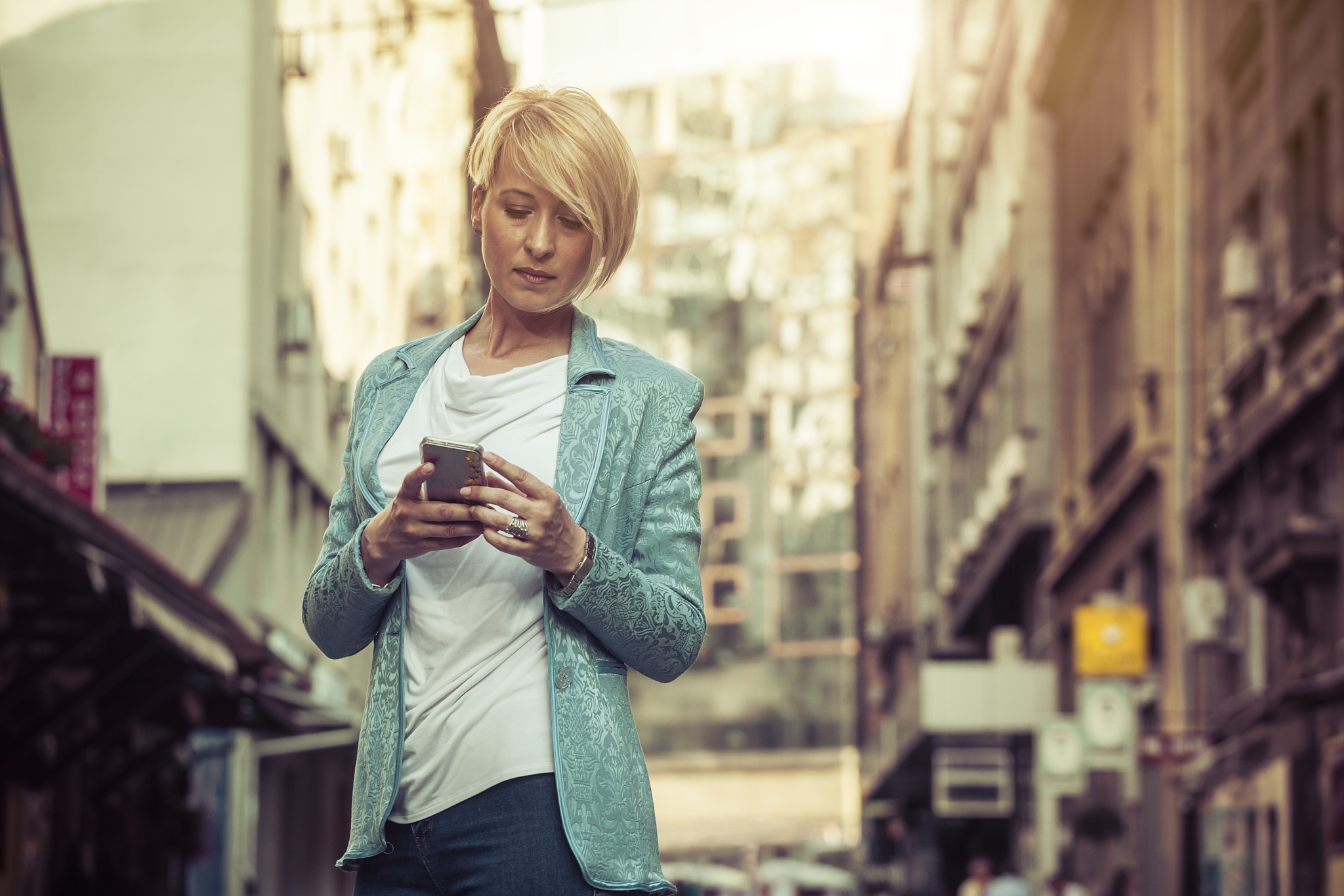stylish mid-age business woman texting on the street