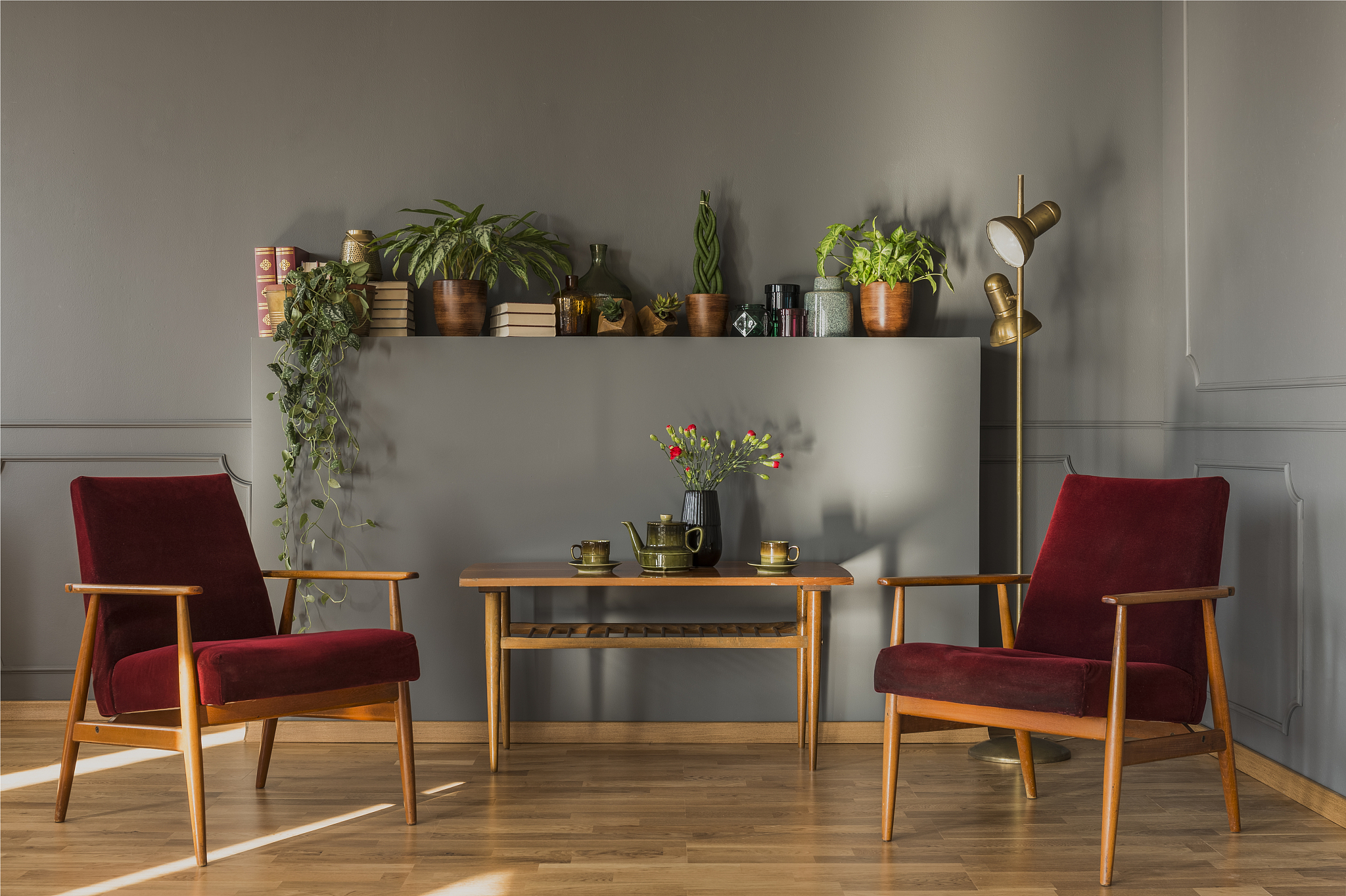 flowers on wooden table between dark red armchairs in simple gre