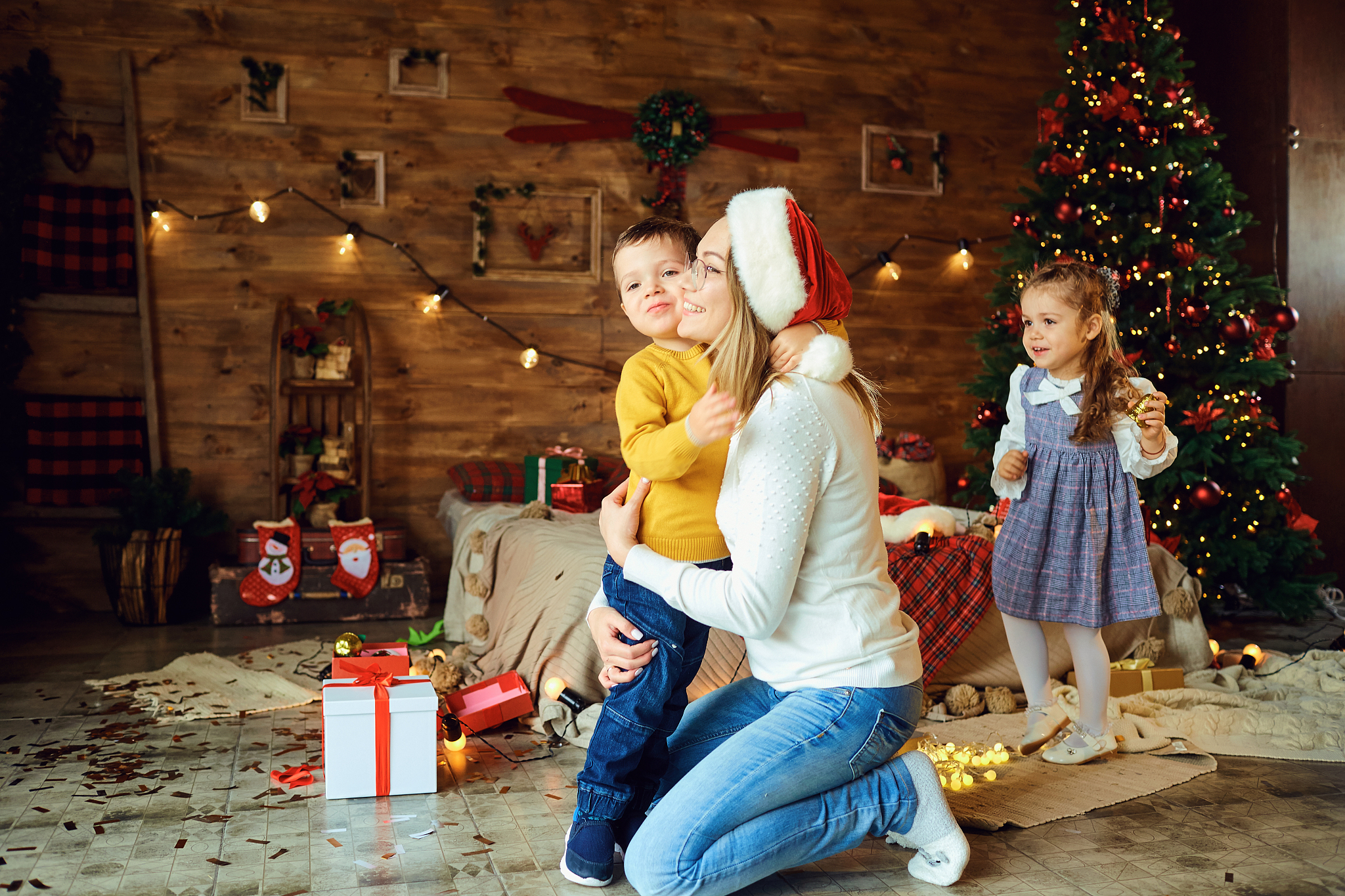 happy mom hugs children in a room at christmas