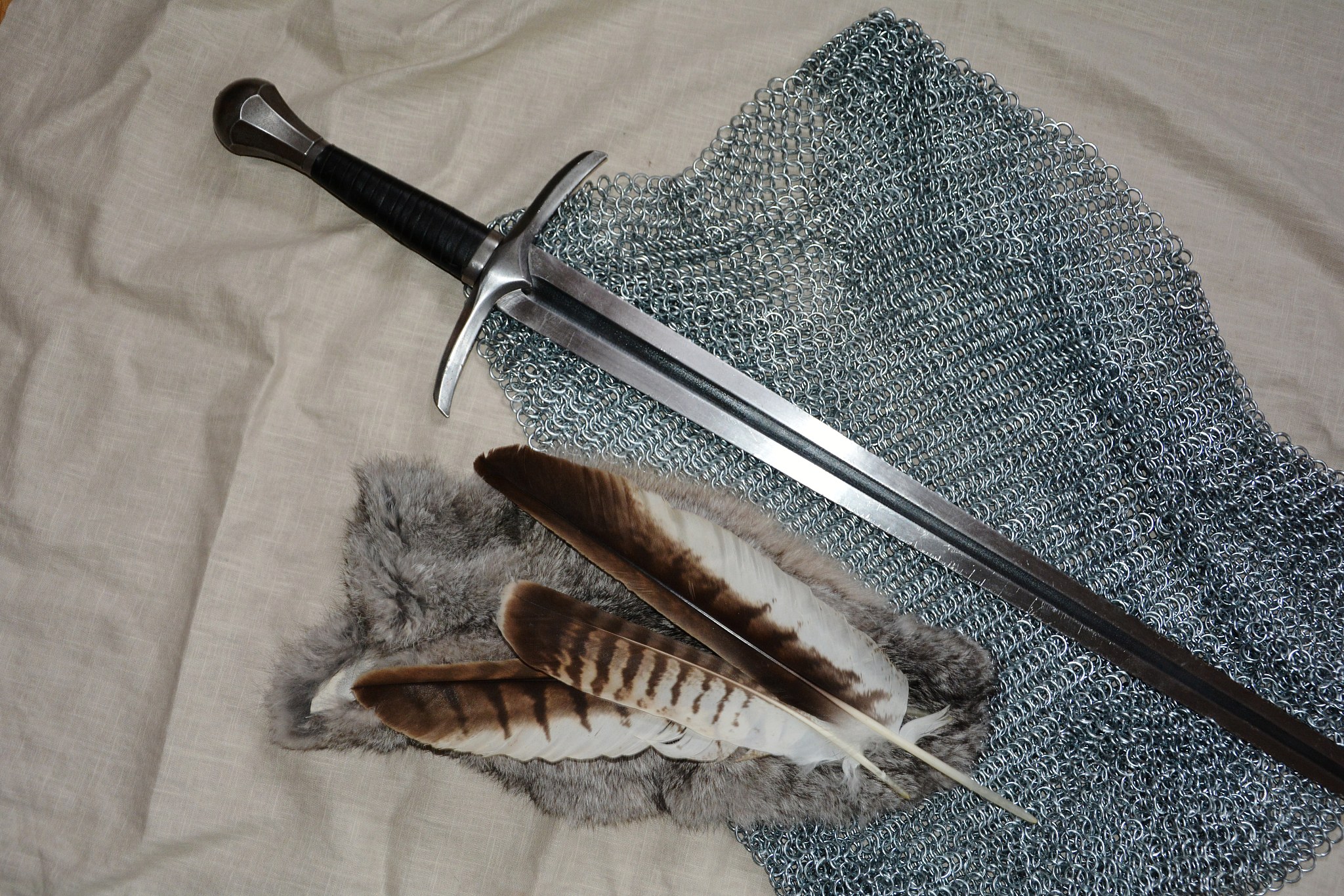 a sword with feathers and chain shirt